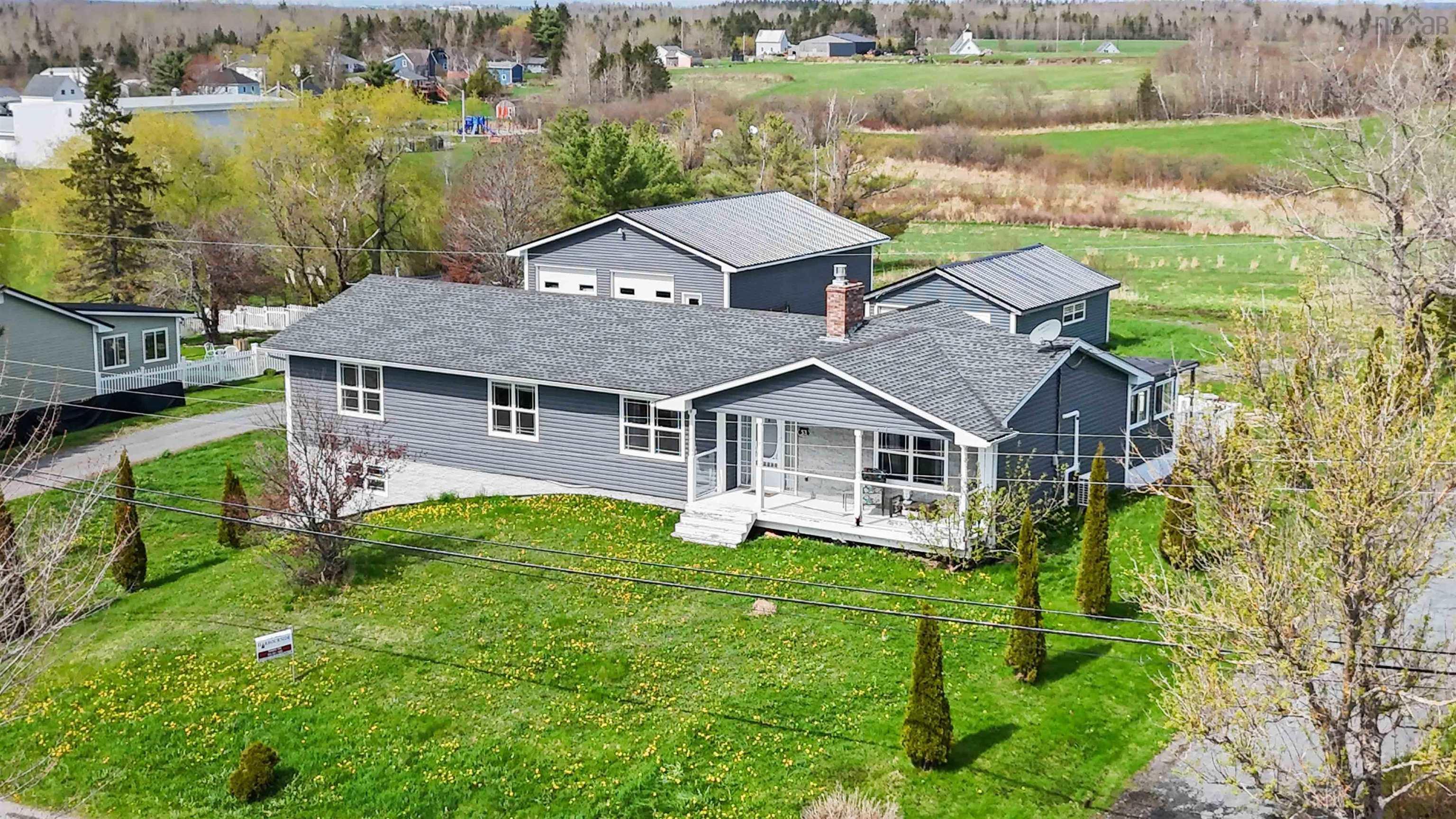 Rear view of house with a deck, a lawn, and a shingled roof