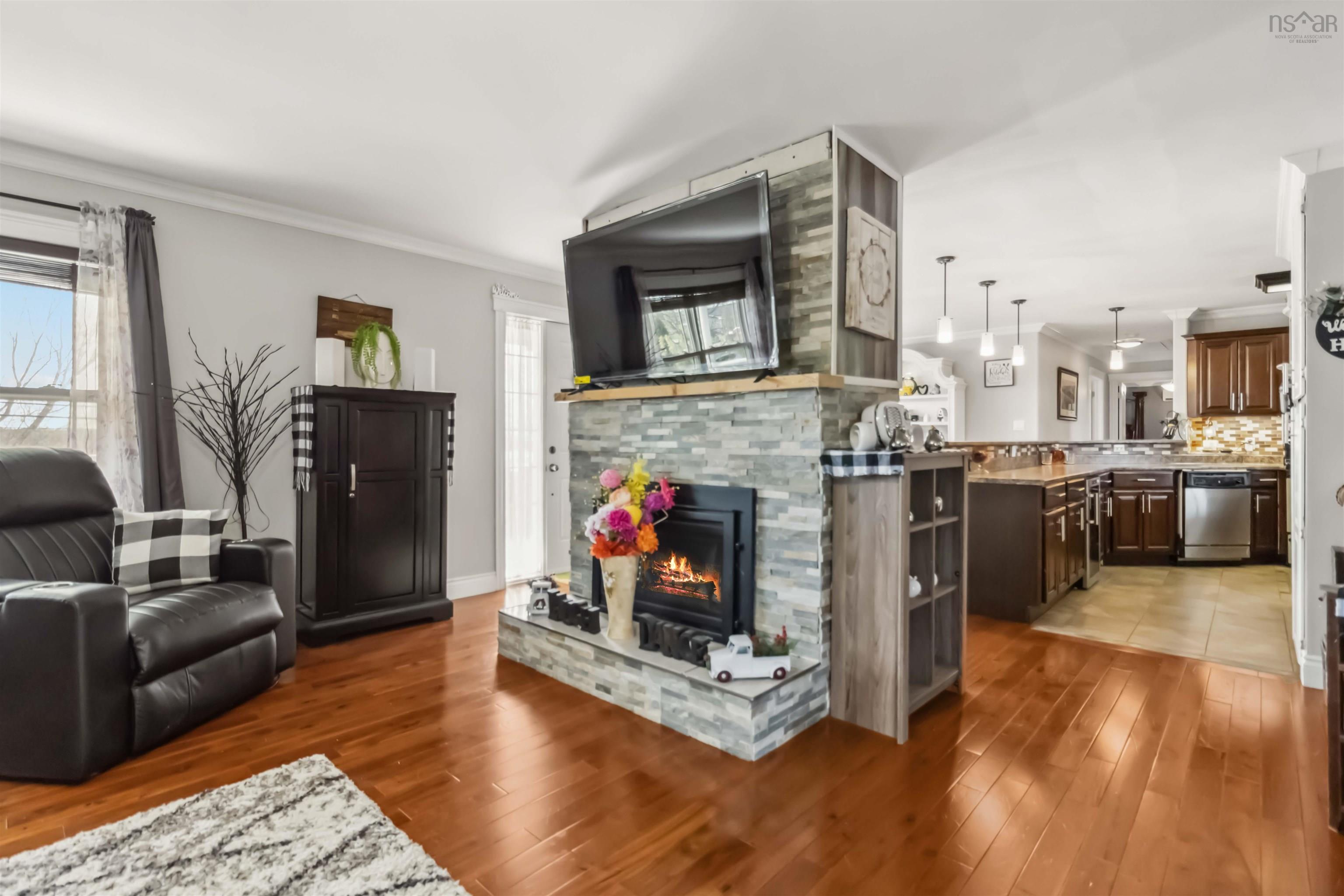 Living room featuring plenty of natural light, ornamental molding, light wood-type flooring, and a fireplace