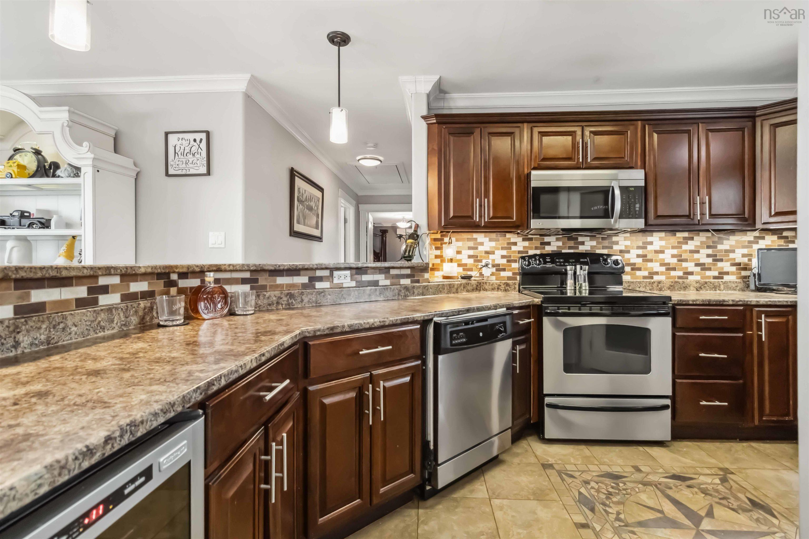 Kitchen with stainless steel appliances, tasteful backsplash, ornamental molding, pendant lighting, and light tile patterned floors