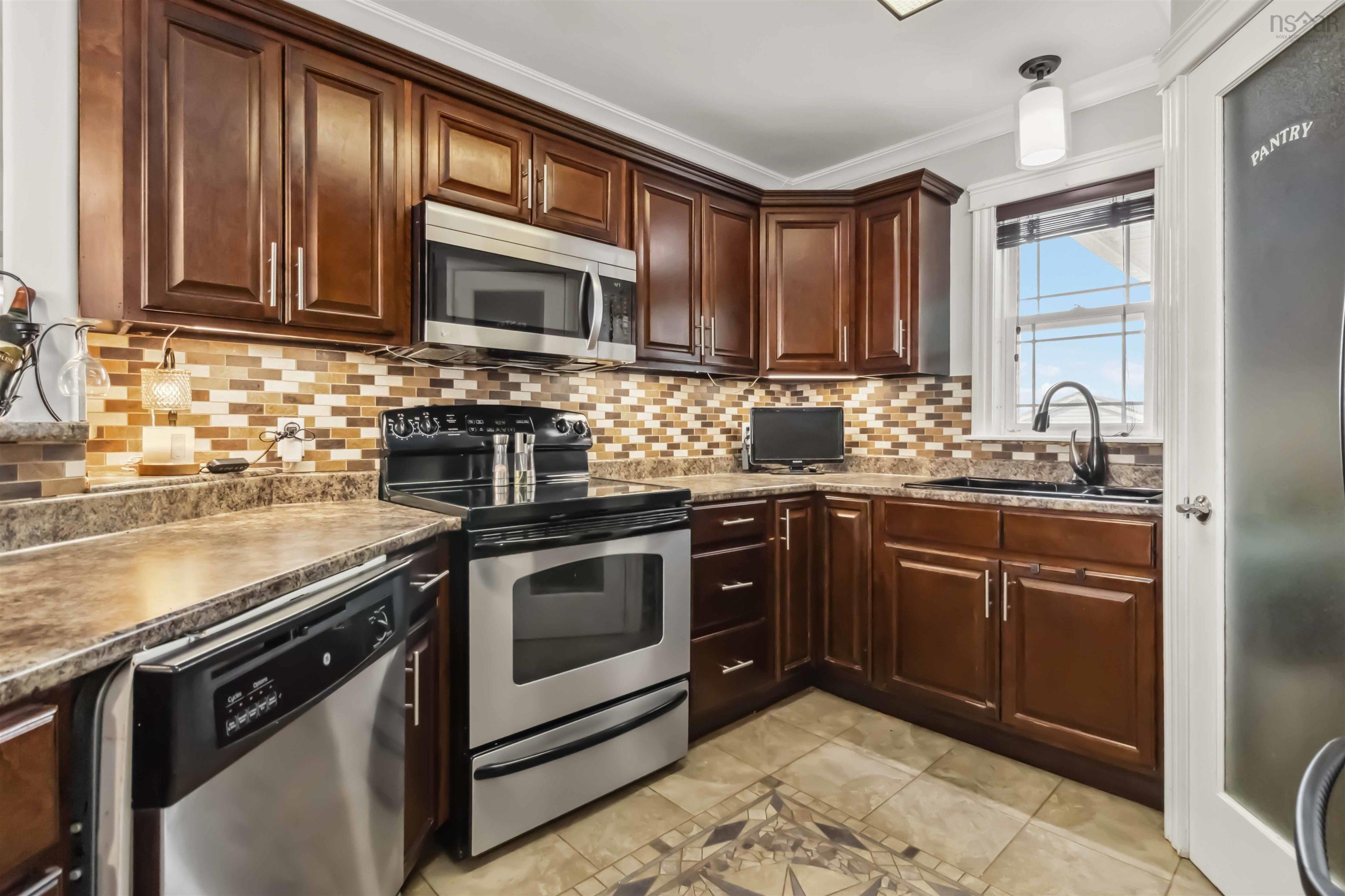Kitchen with appliances with stainless steel finishes, a sink, ornamental molding, decorative backsplash, and light tile patterned flooring