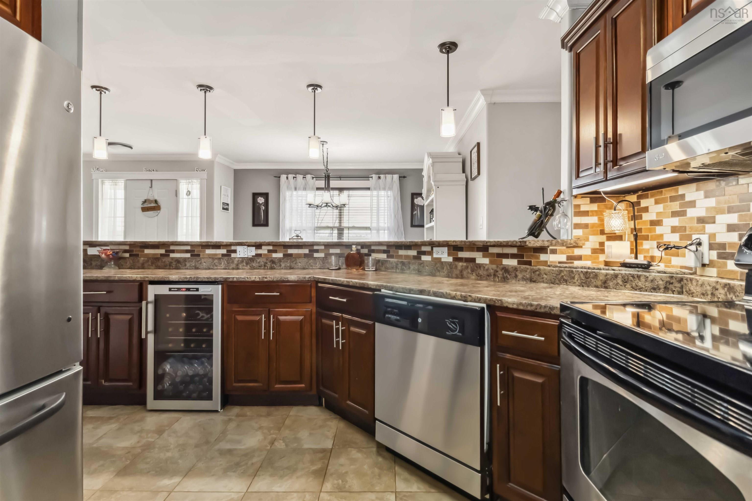 Kitchen featuring stainless steel appliances, beverage cooler, crown molding, tasteful backsplash, and decorative light fixtures