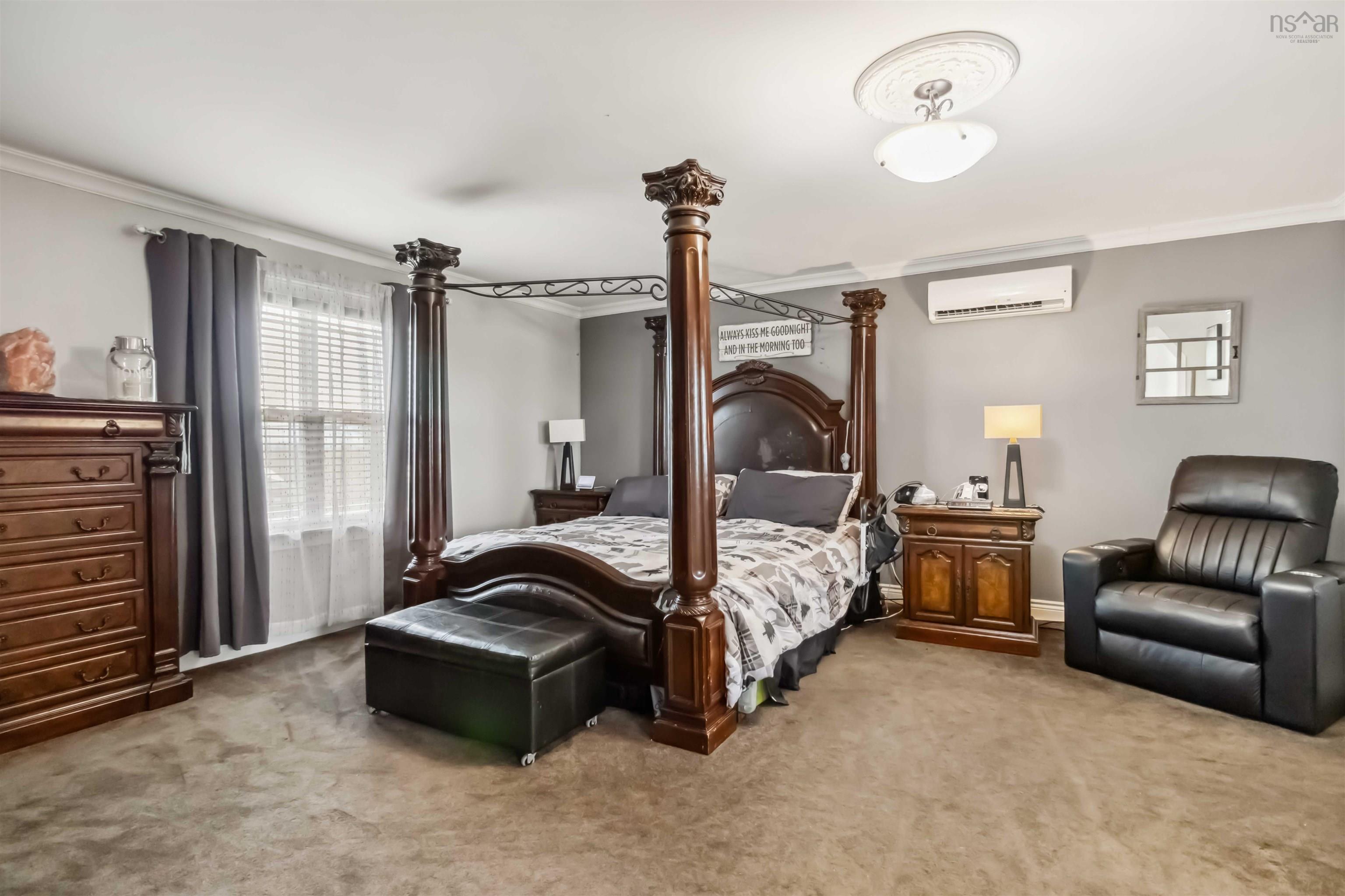 Bedroom with ornamental molding, a wall mounted AC, and carpet