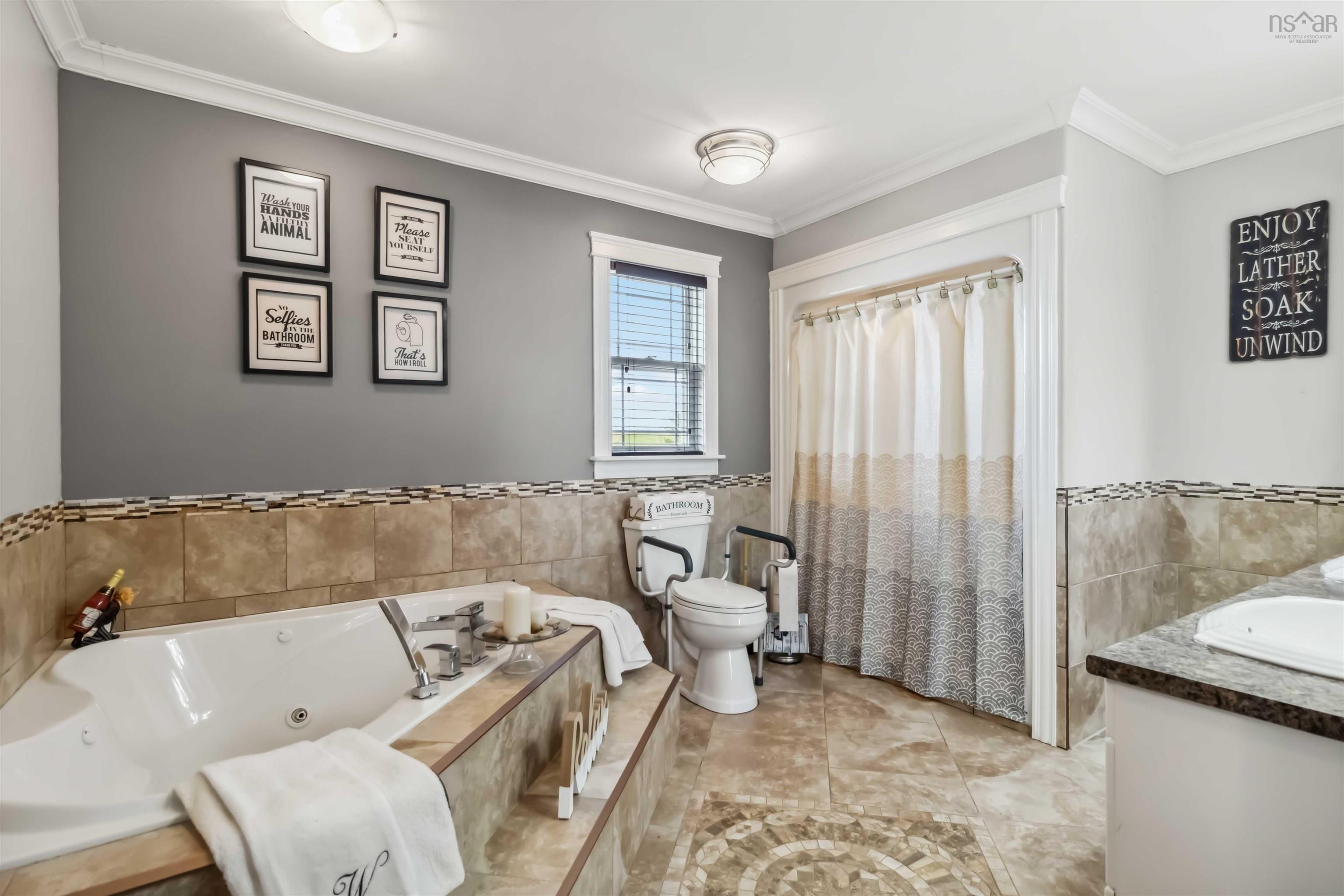 Full bath featuring ornamental molding, tile walls, a tub with jets, toilet, and vanity