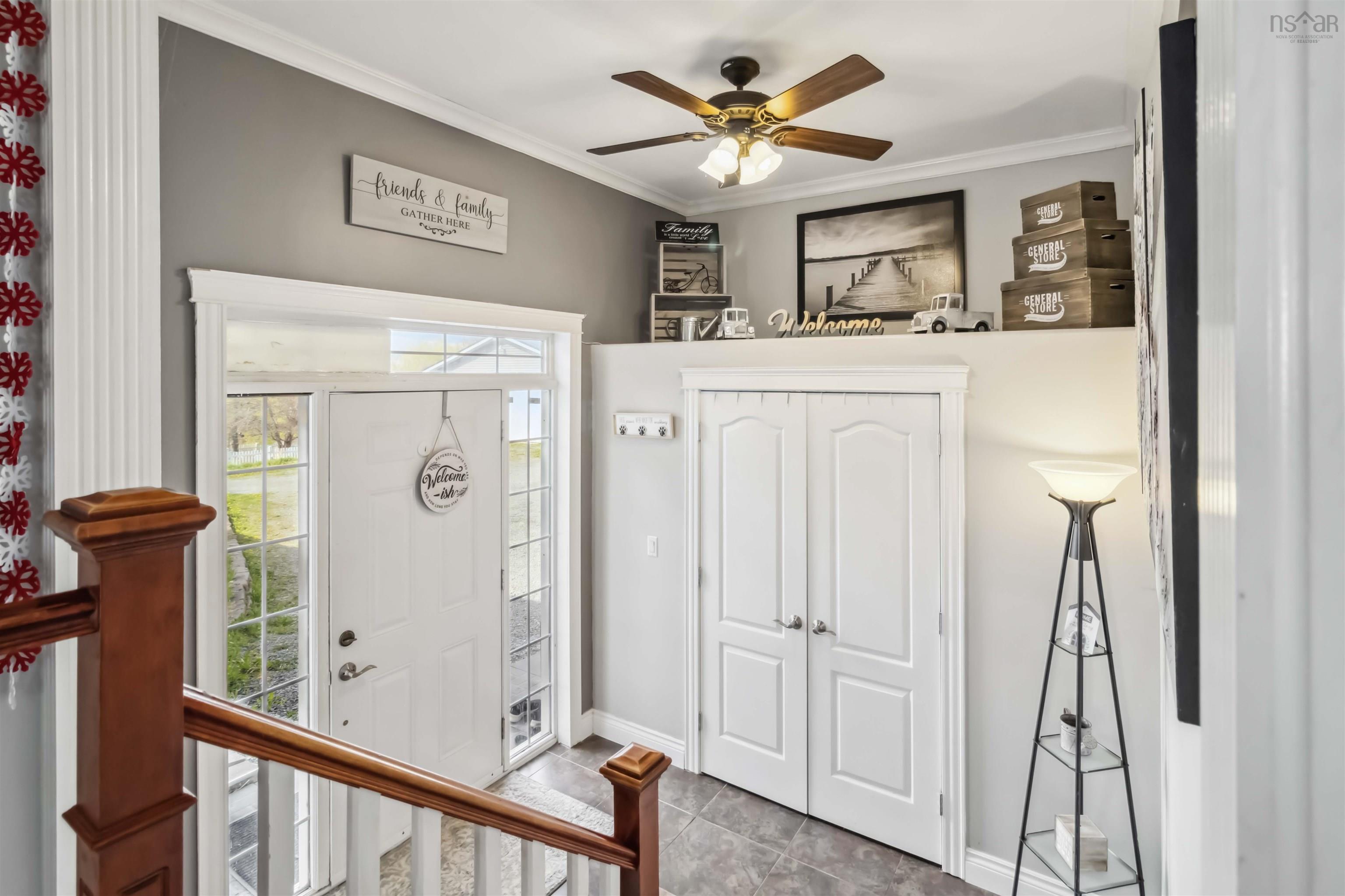 Tiled foyer with healthy amount of natural light, baseboards, a ceiling fan, and ornamental molding