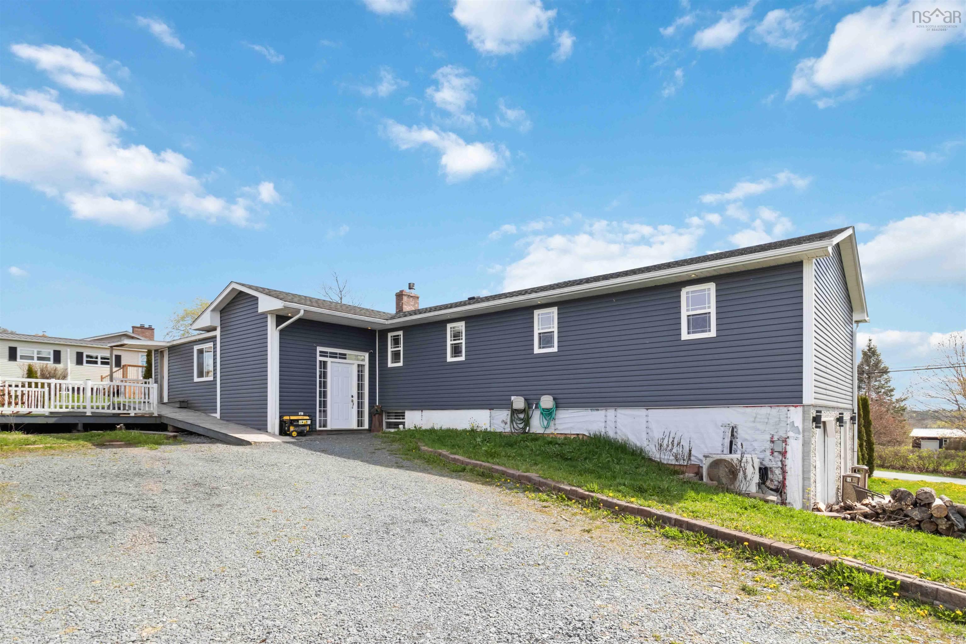 Back of house with a wooden deck, a chimney, and gravel driveway