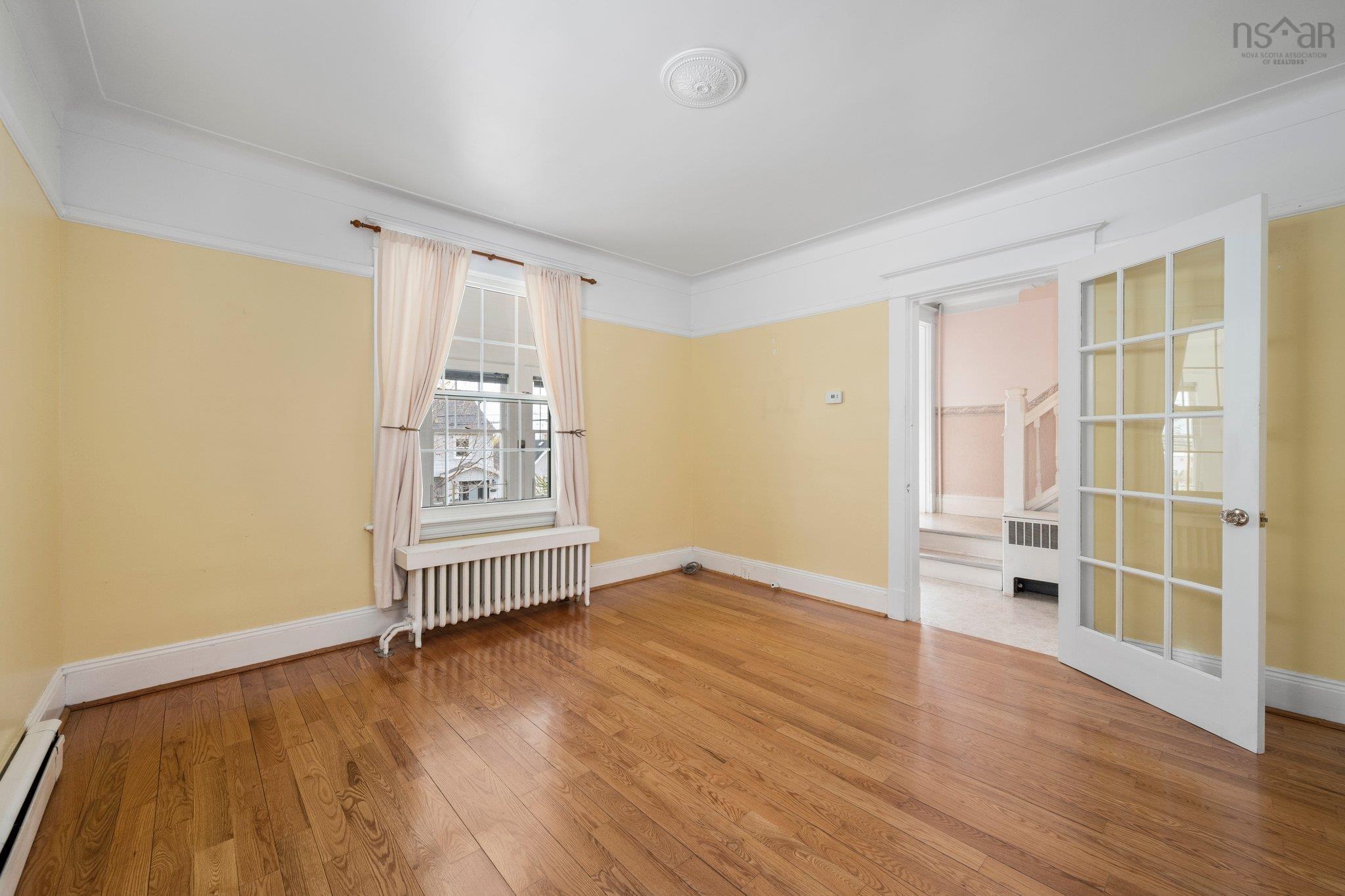 Unfurnished room with radiator heating unit, wood finished floors, radiator, baseboards, and ornamental molding