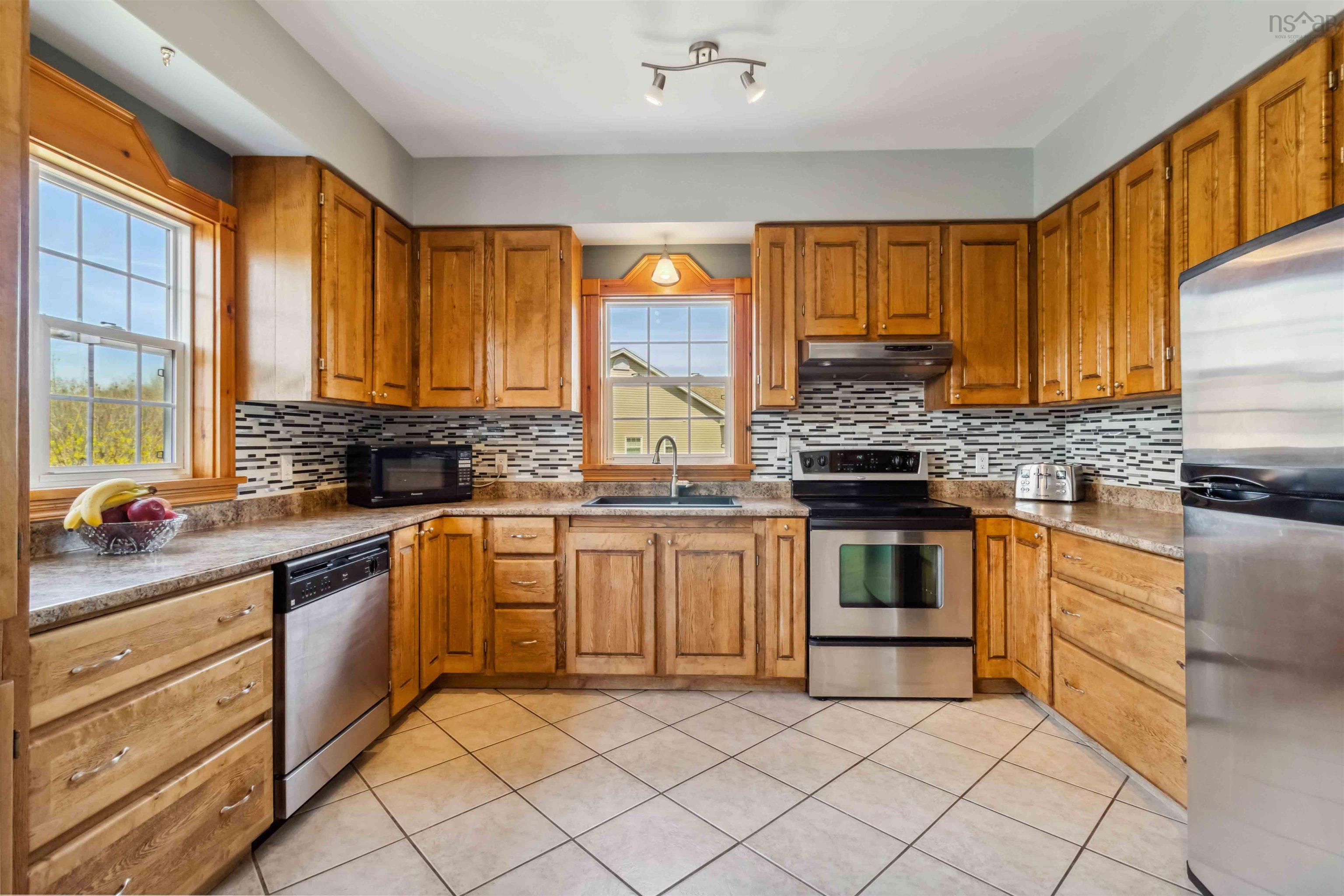 Kitchen featuring stainless steel appliances, under cabinet range hood, a sink, and decorative backsplash