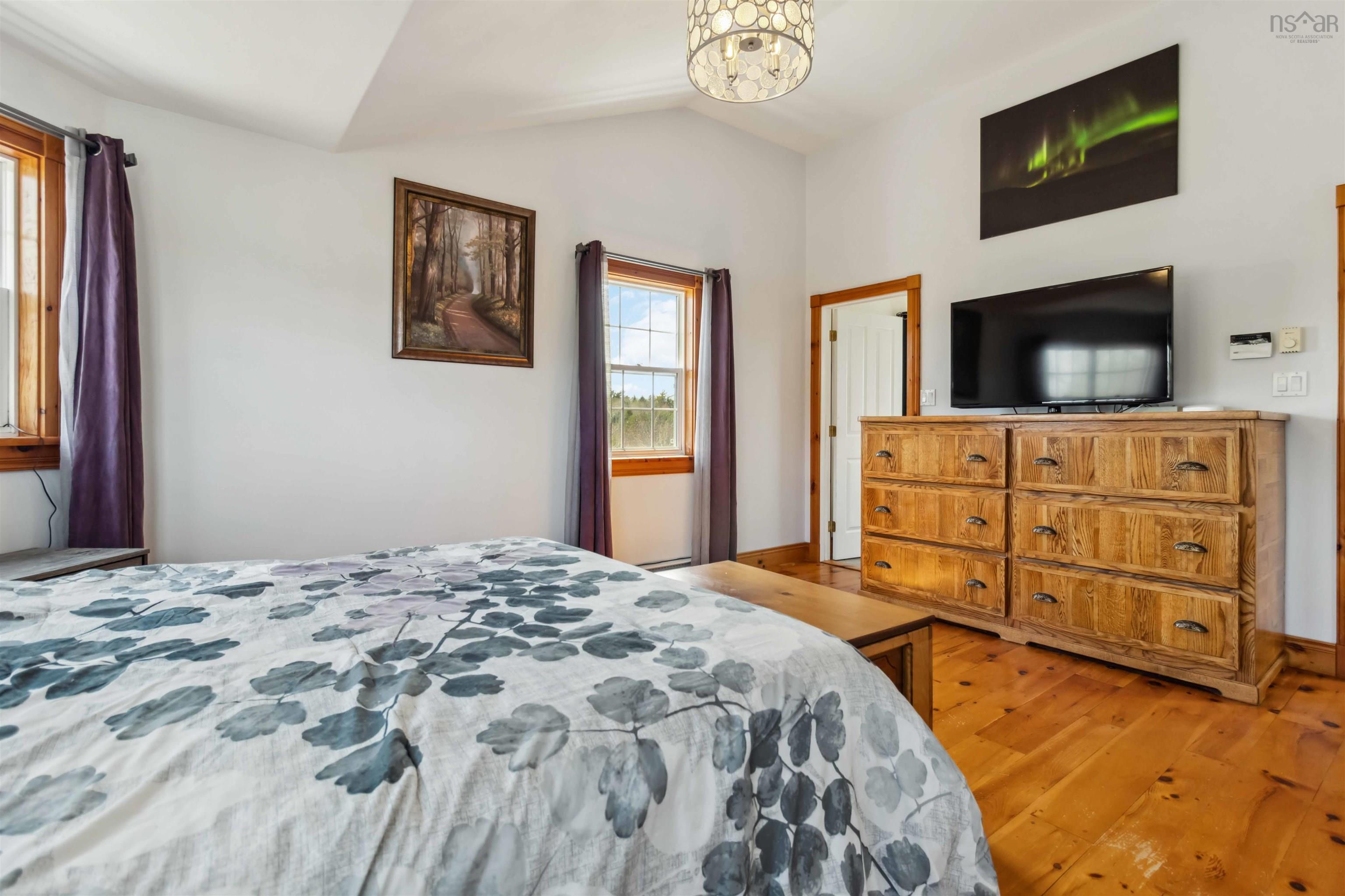 Bedroom with light wood-type flooring, lofted ceiling, baseboards, and a chandelier