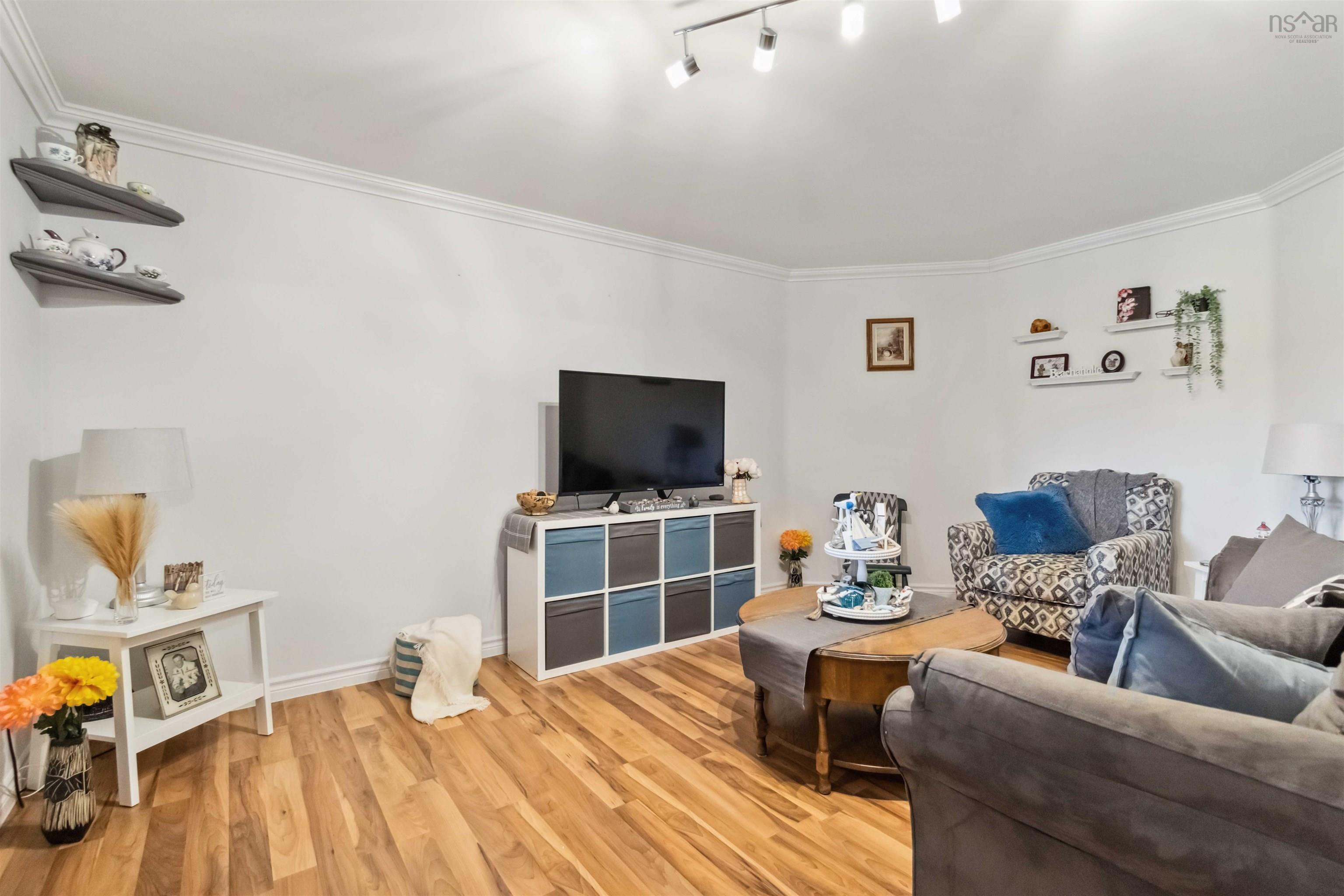 Living room with light wood finished floors, crown molding, and baseboards