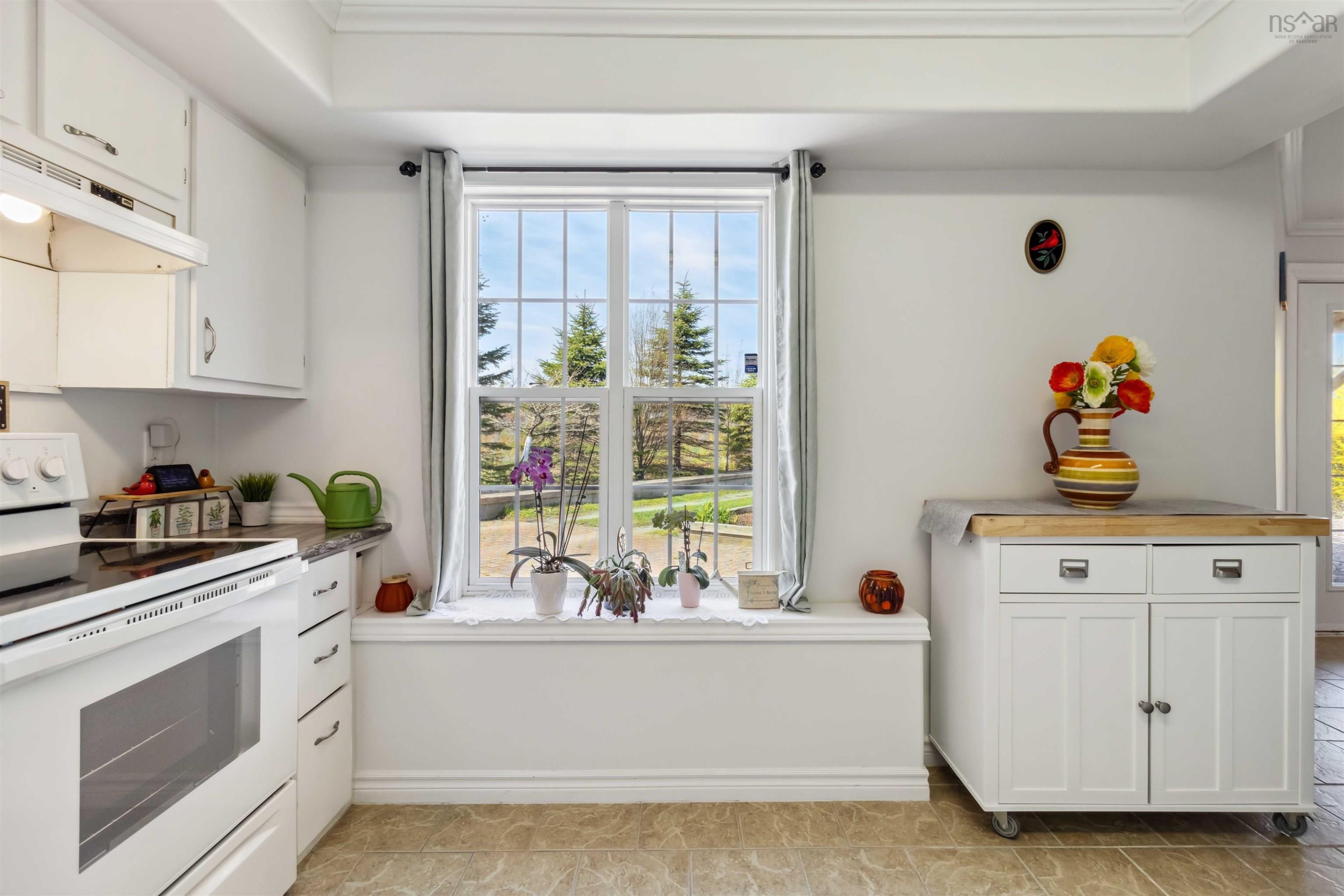 Kitchen with white range with electric stovetop, under cabinet range hood, plenty of natural light, and white cabinetry
