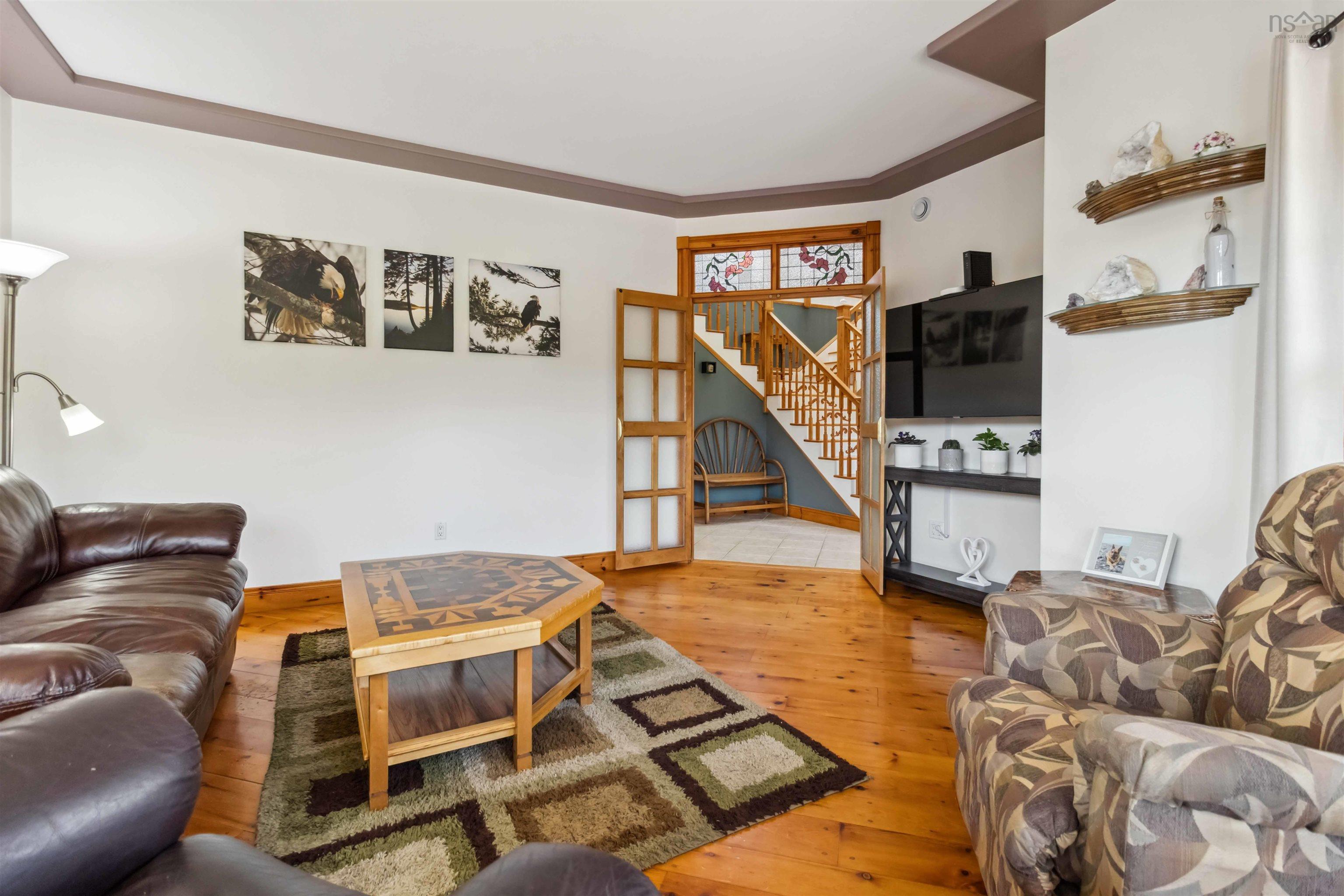 Living area with hardwood / wood-style flooring, stairway, crown molding, and baseboards