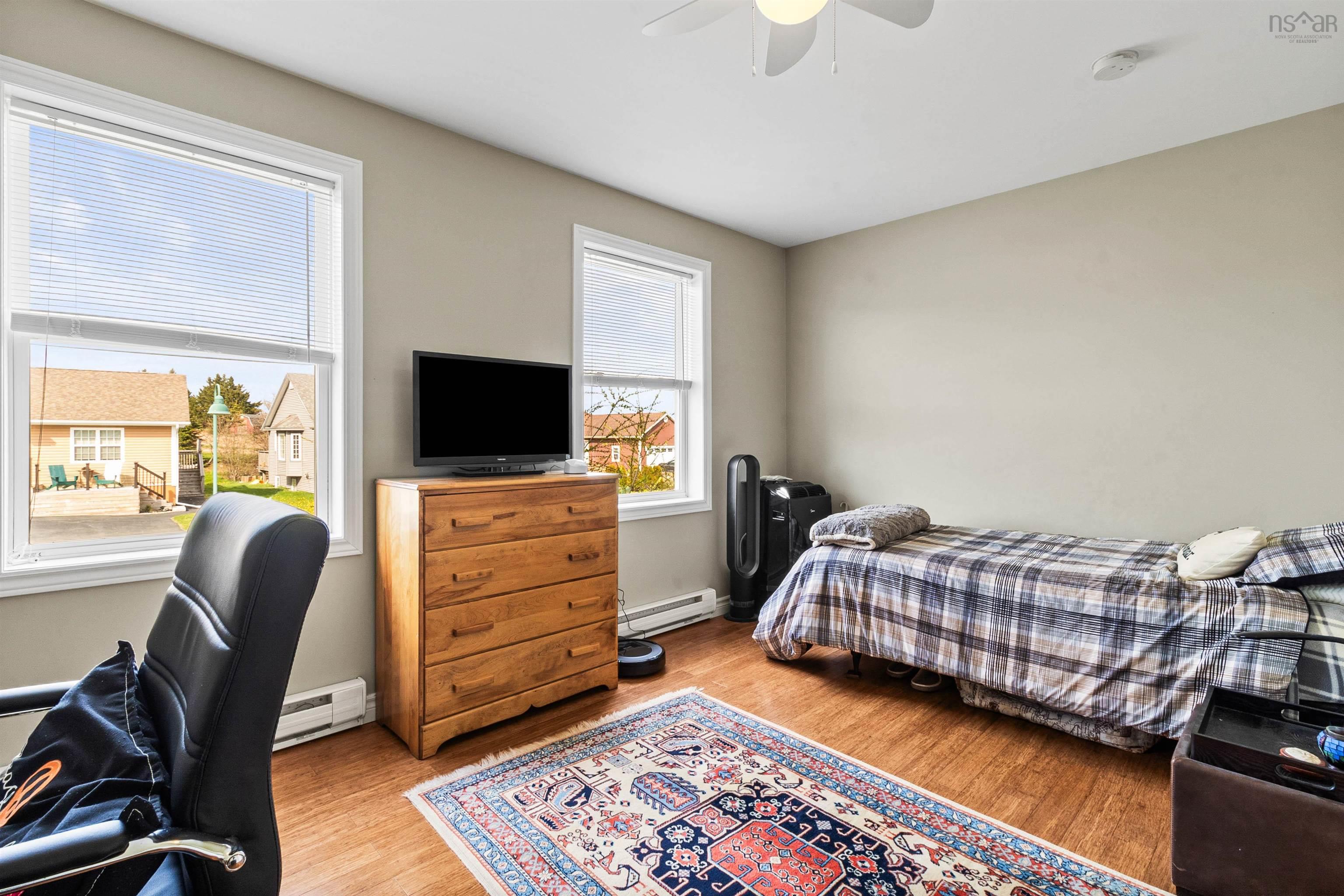 Bedroom with baseboard heating, light wood-style floors, and a ceiling fan