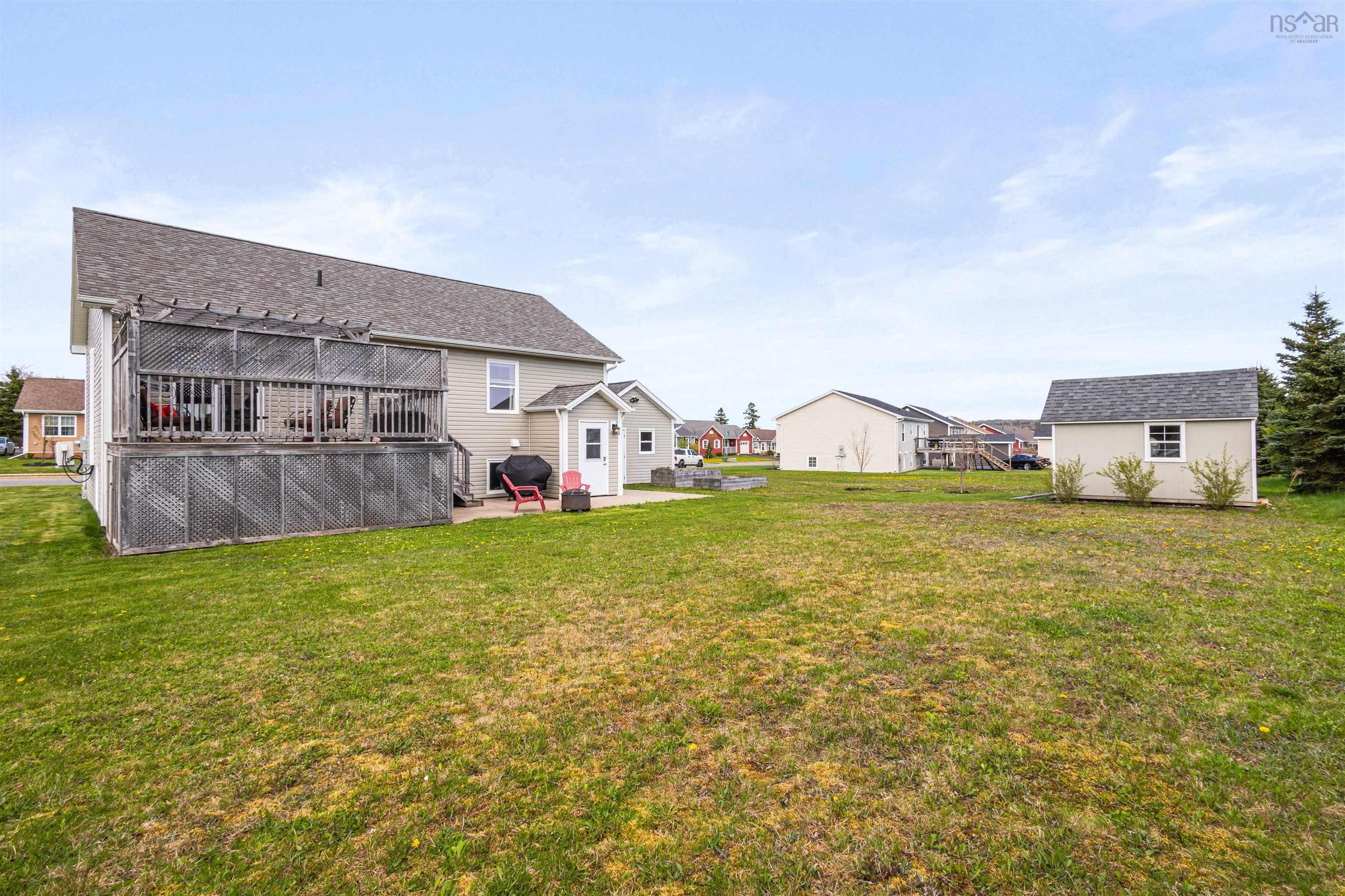 Rear view of property with a wooden deck, a patio area, a yard, and an outbuilding