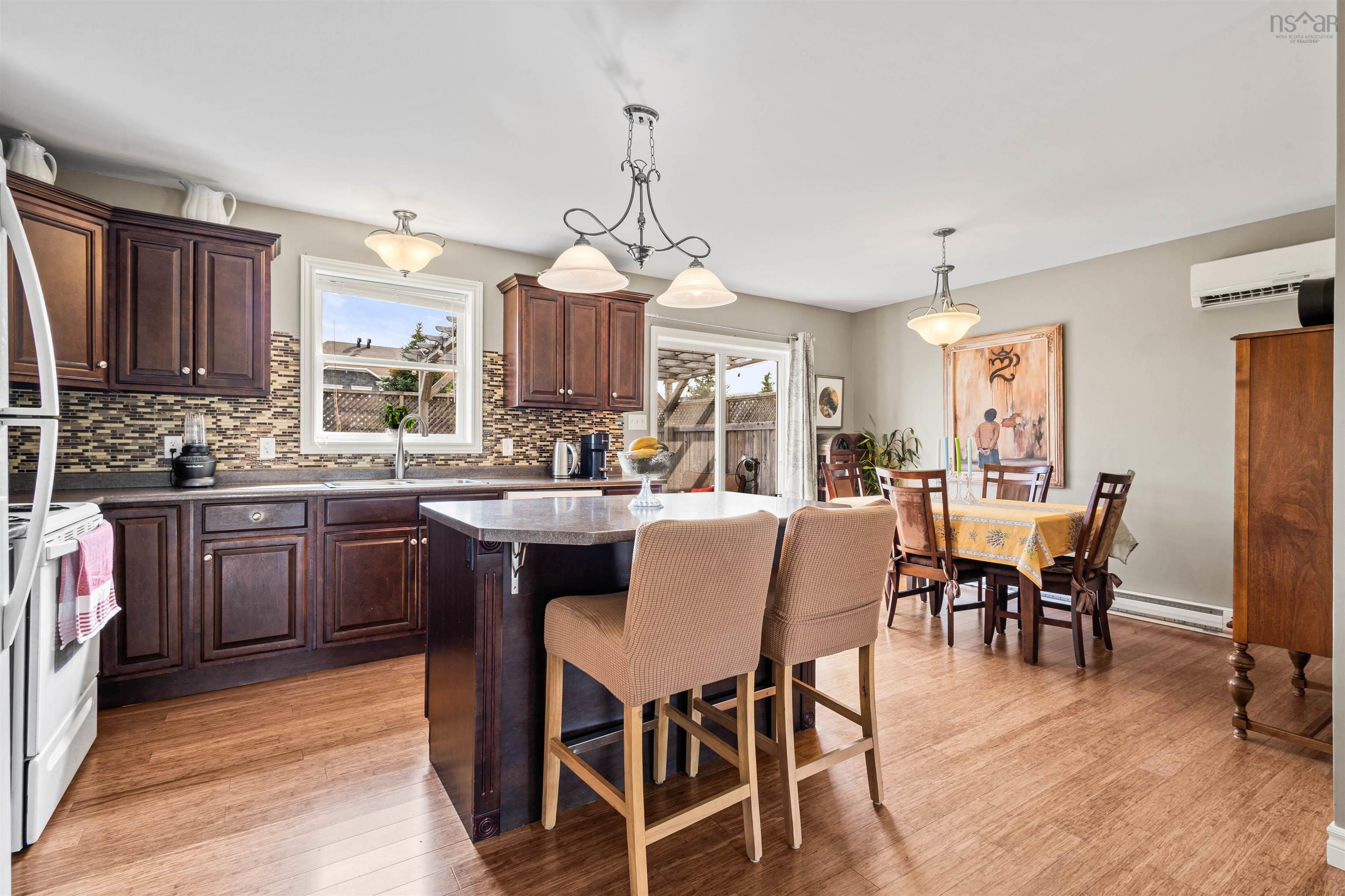 Kitchen featuring a wall mounted AC, a sink, backsplash, light wood-style flooring, and a kitchen bar