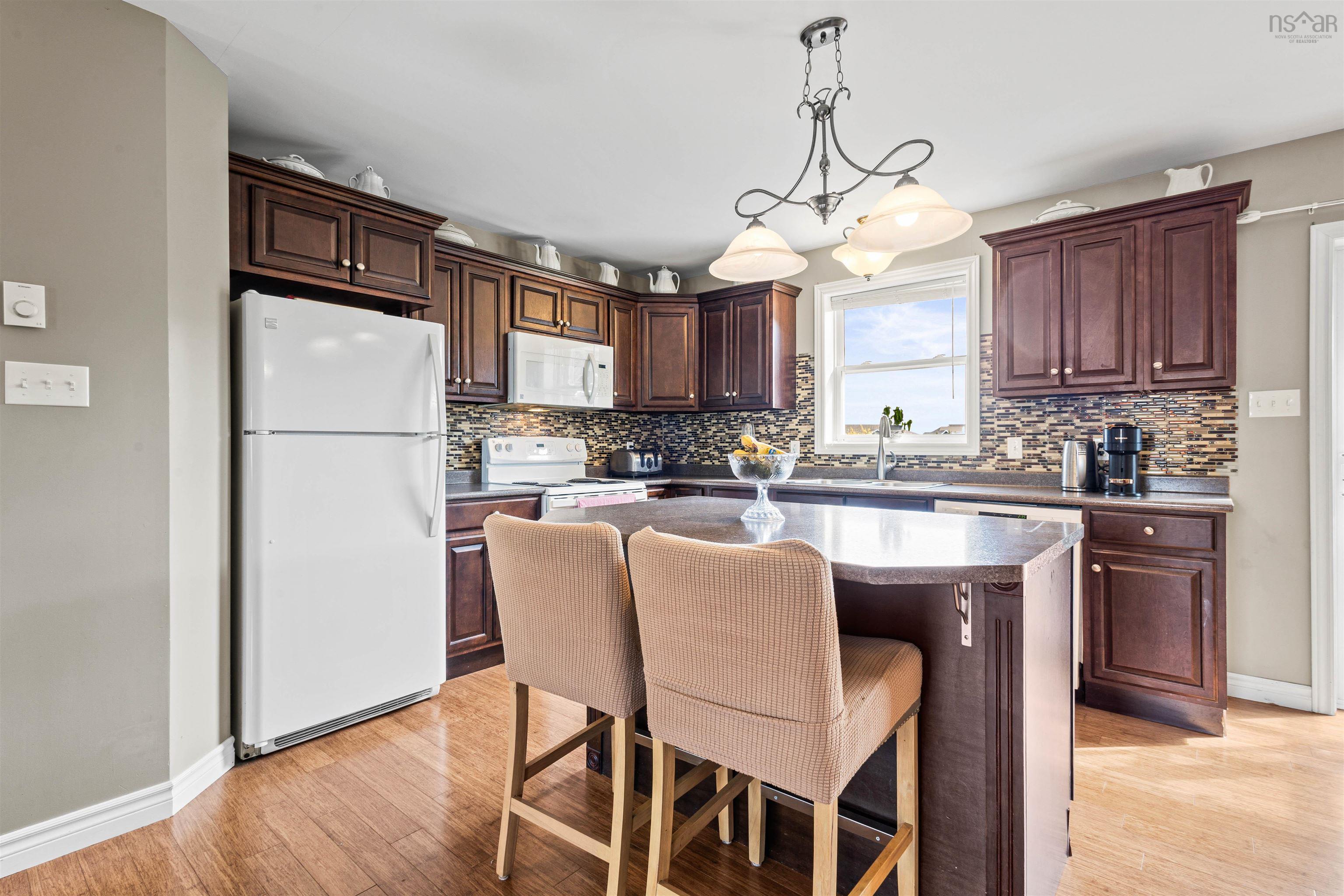 Kitchen featuring white appliances, light wood-type flooring, backsplash, a sink, and baseboards