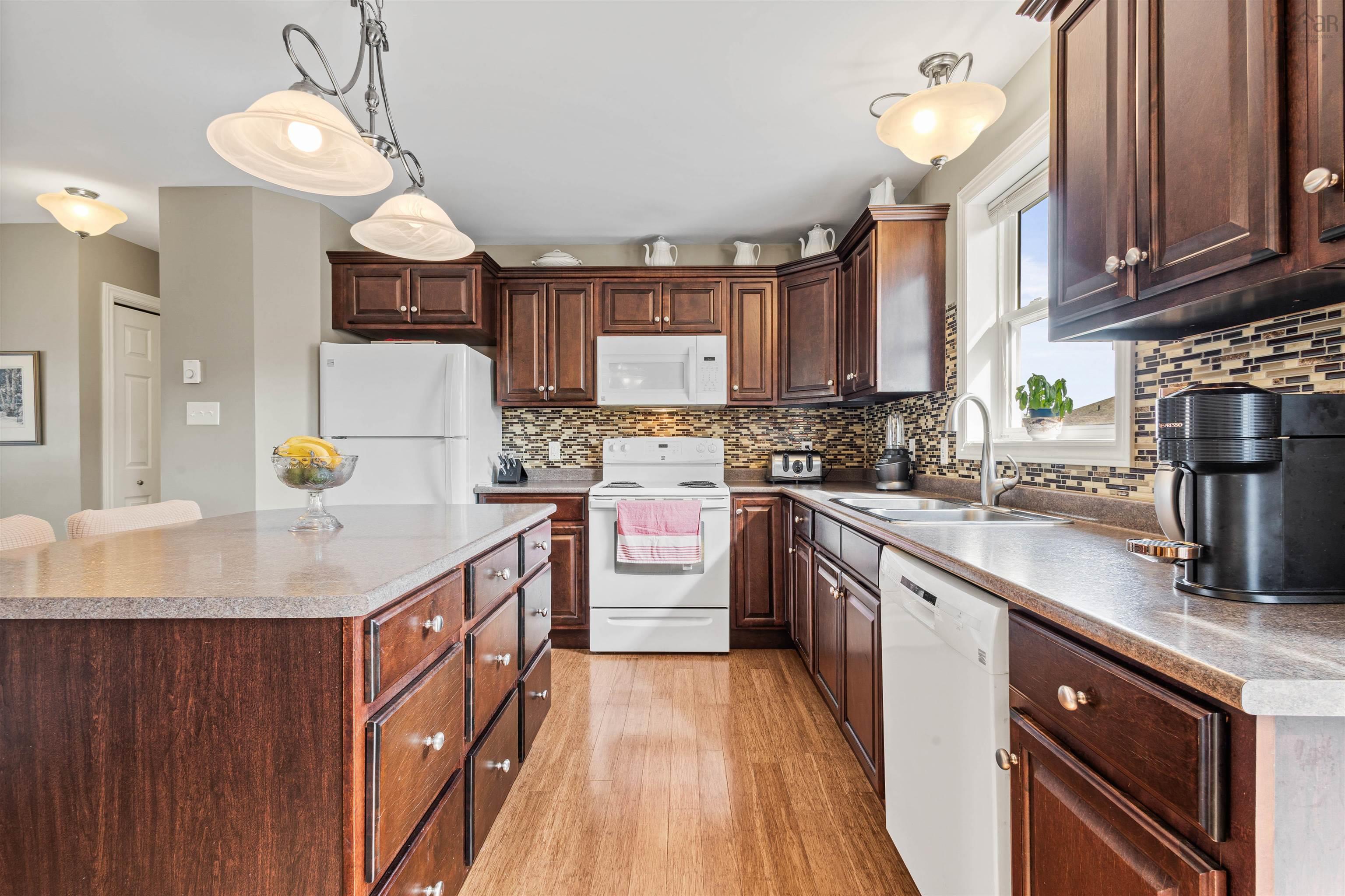 Kitchen featuring white appliances, a sink, decorative backsplash, a center island, and light wood-style floors