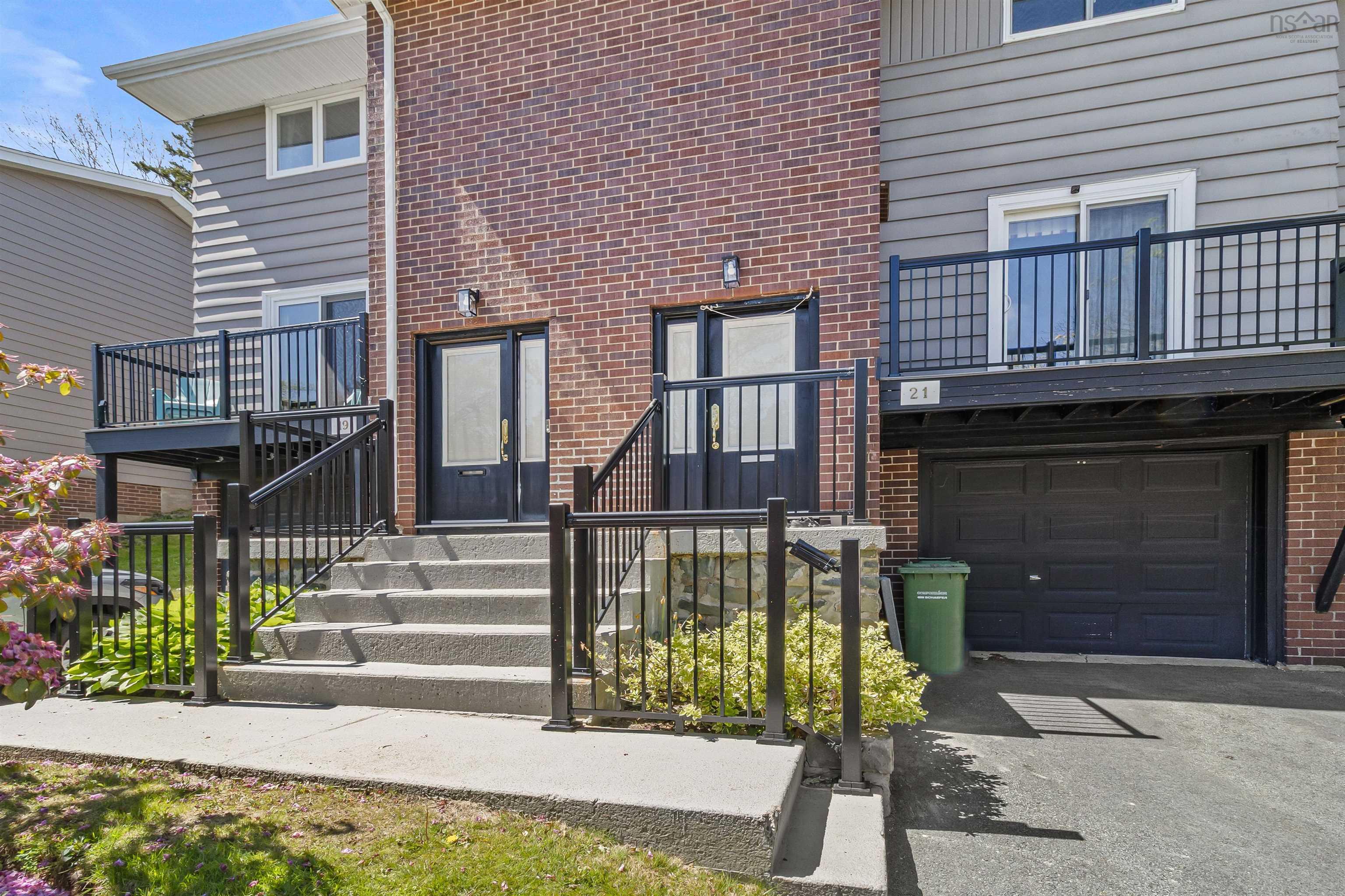 Doorway to property with brick siding, an attached garage, a balcony, and driveway