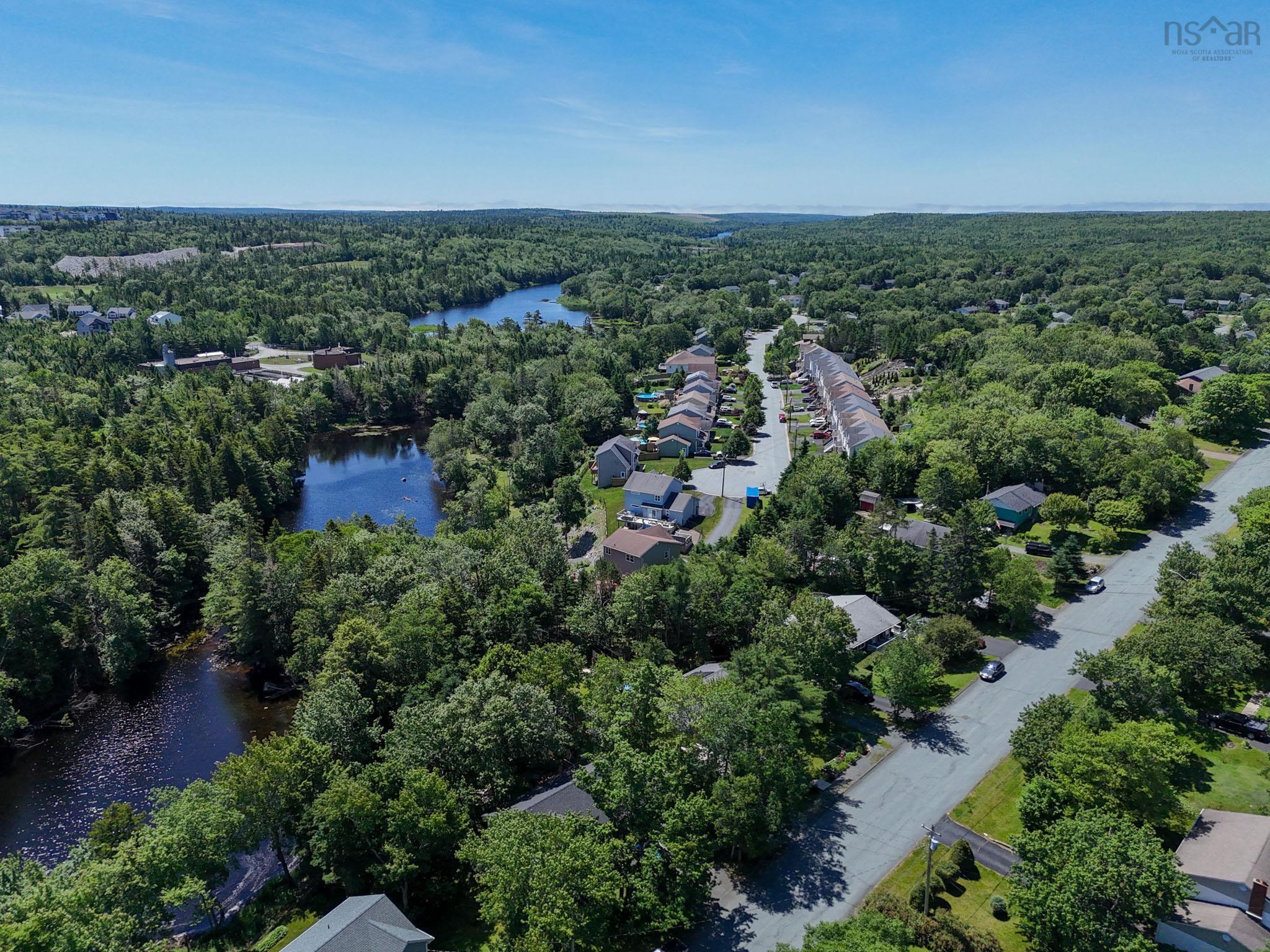 Aerial view of property and surrounding area featuring a heavily wooded area and a nearby body of water