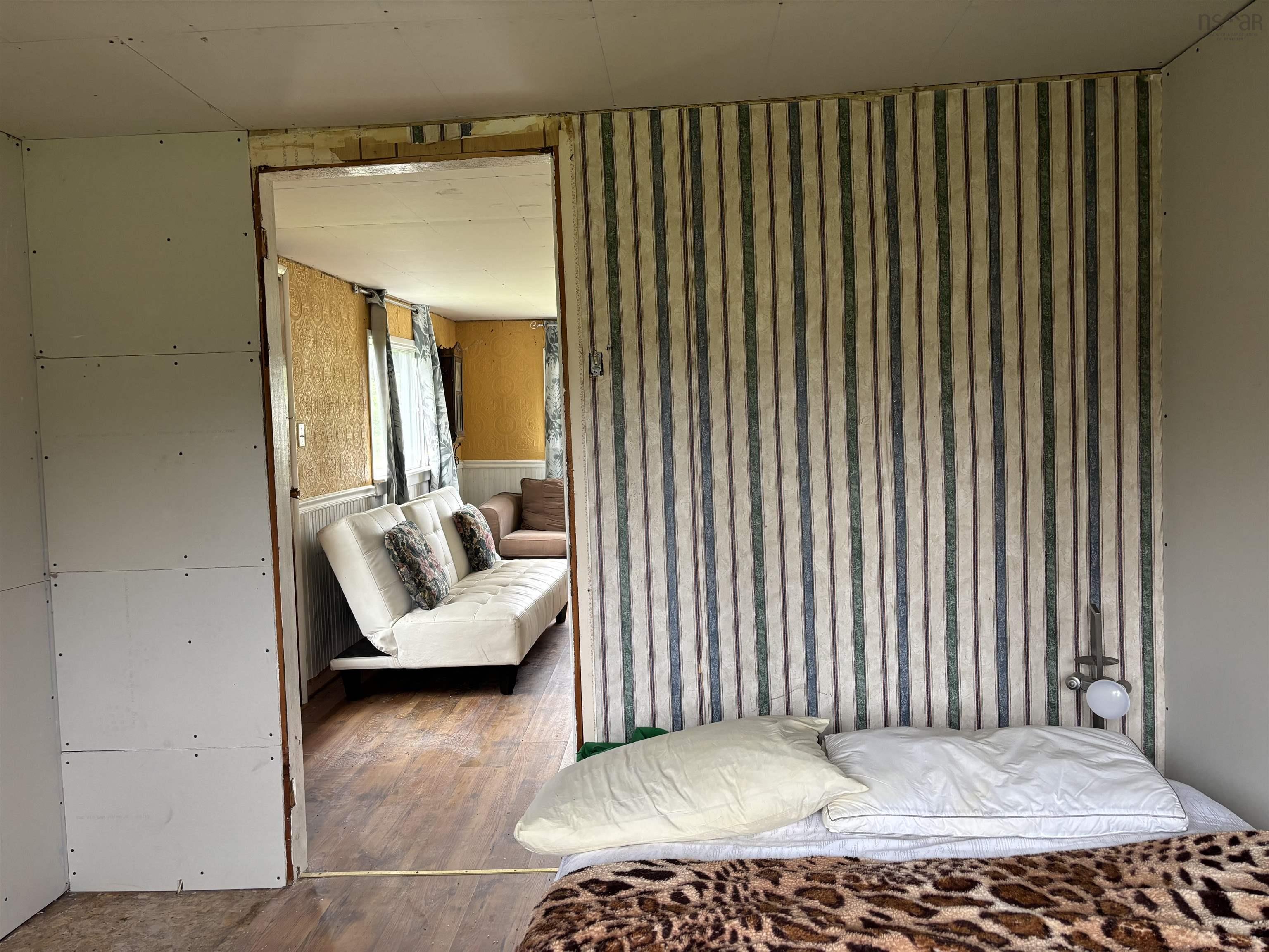 Bedroom with wood finished floors and wallpapered walls