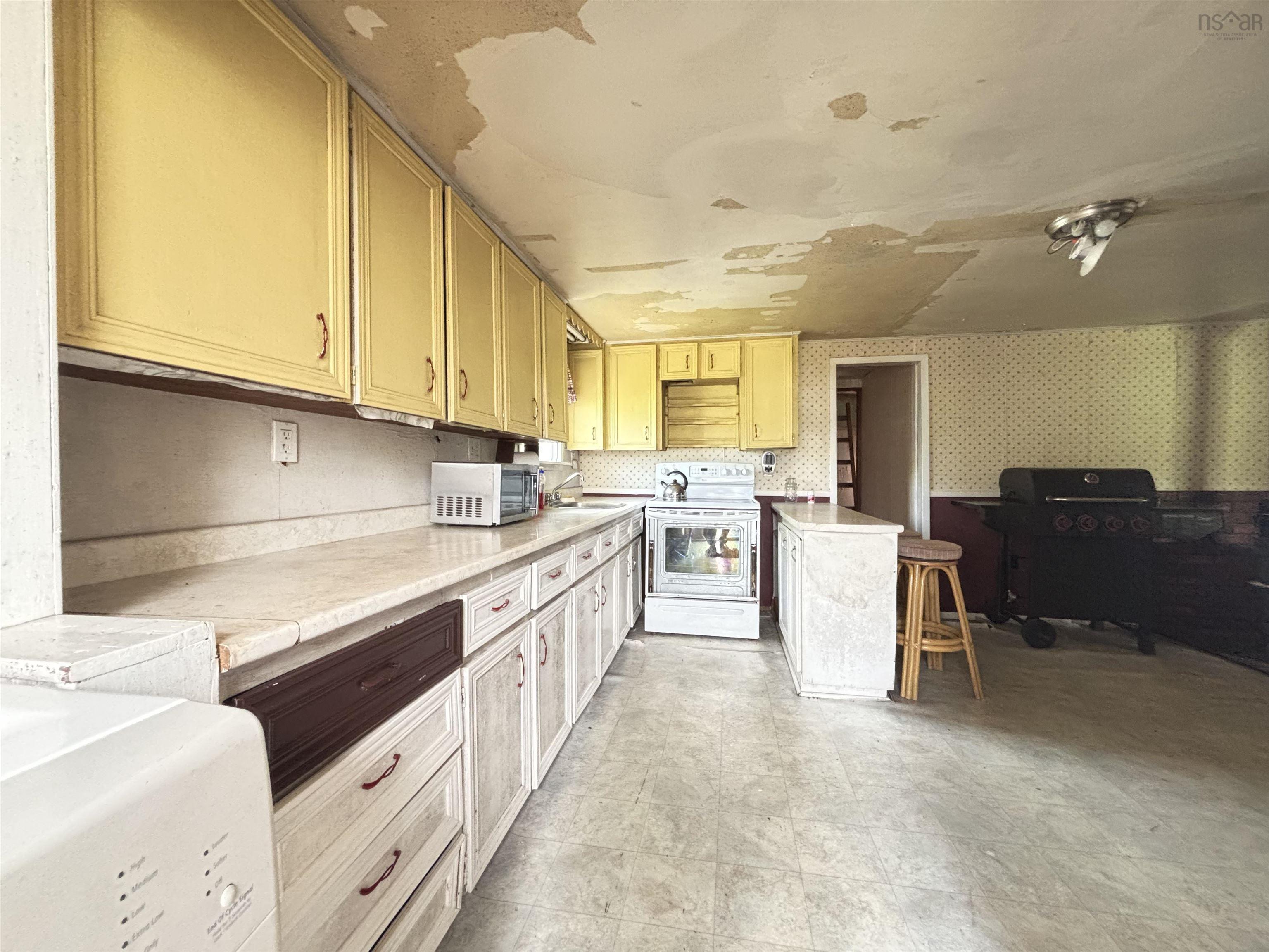 Kitchen featuring electric range, light countertops, and wallpapered walls