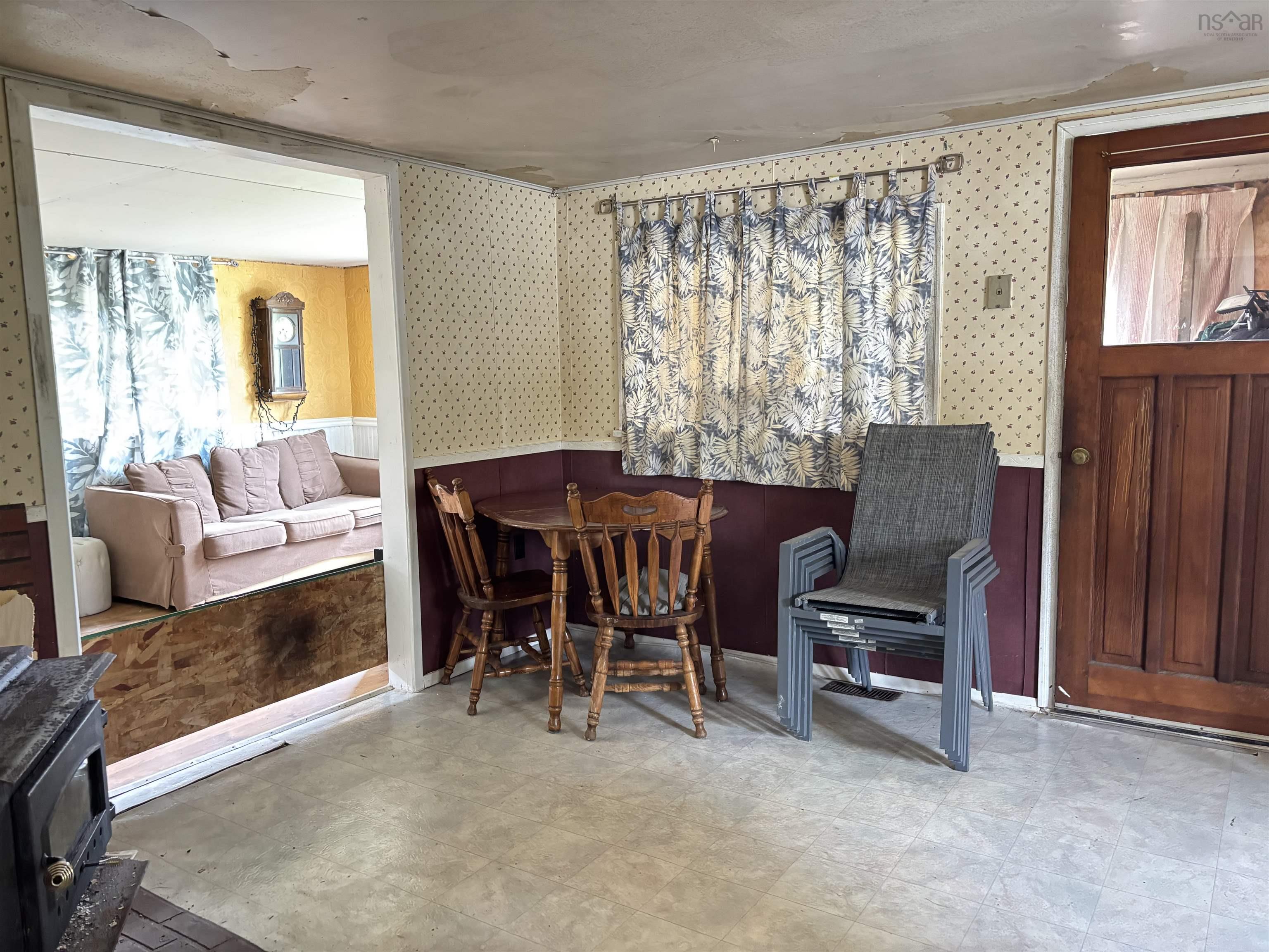 Dining room featuring wallpapered walls, light flooring, and a wood stove