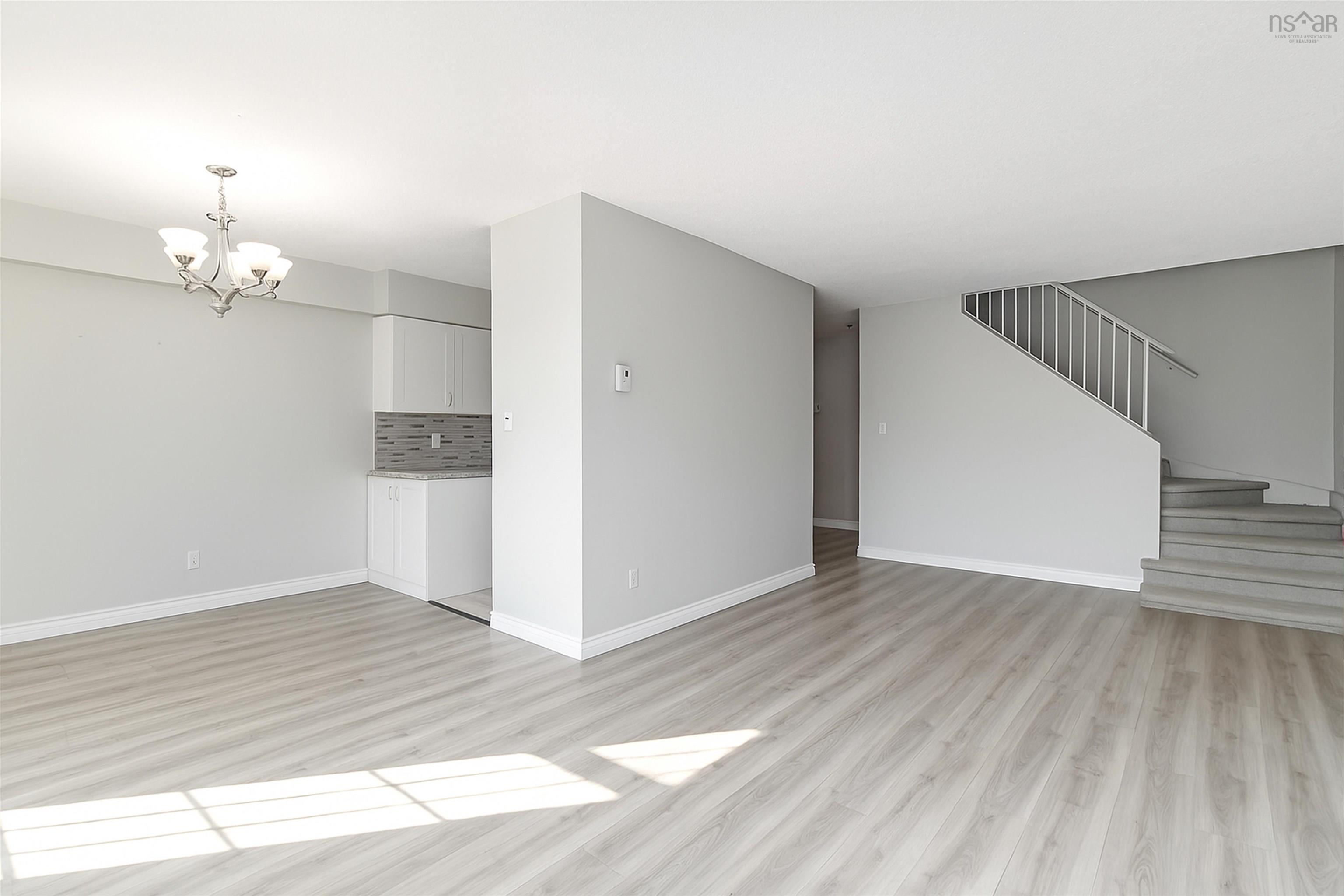 Unfurnished living room featuring a chandelier, light wood-type flooring, and stairway