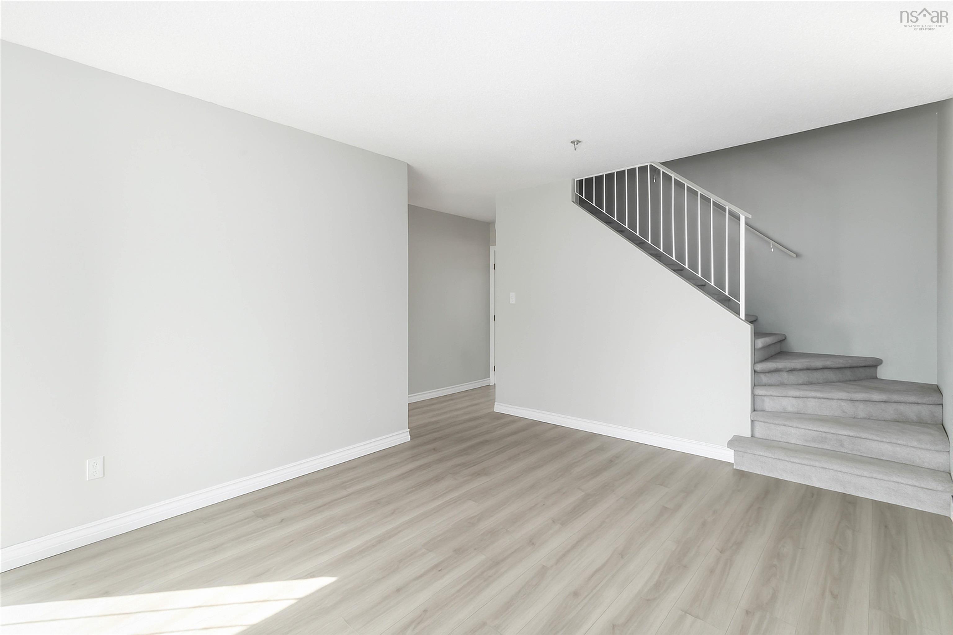 Unfurnished living room with wood finished floors and stairway