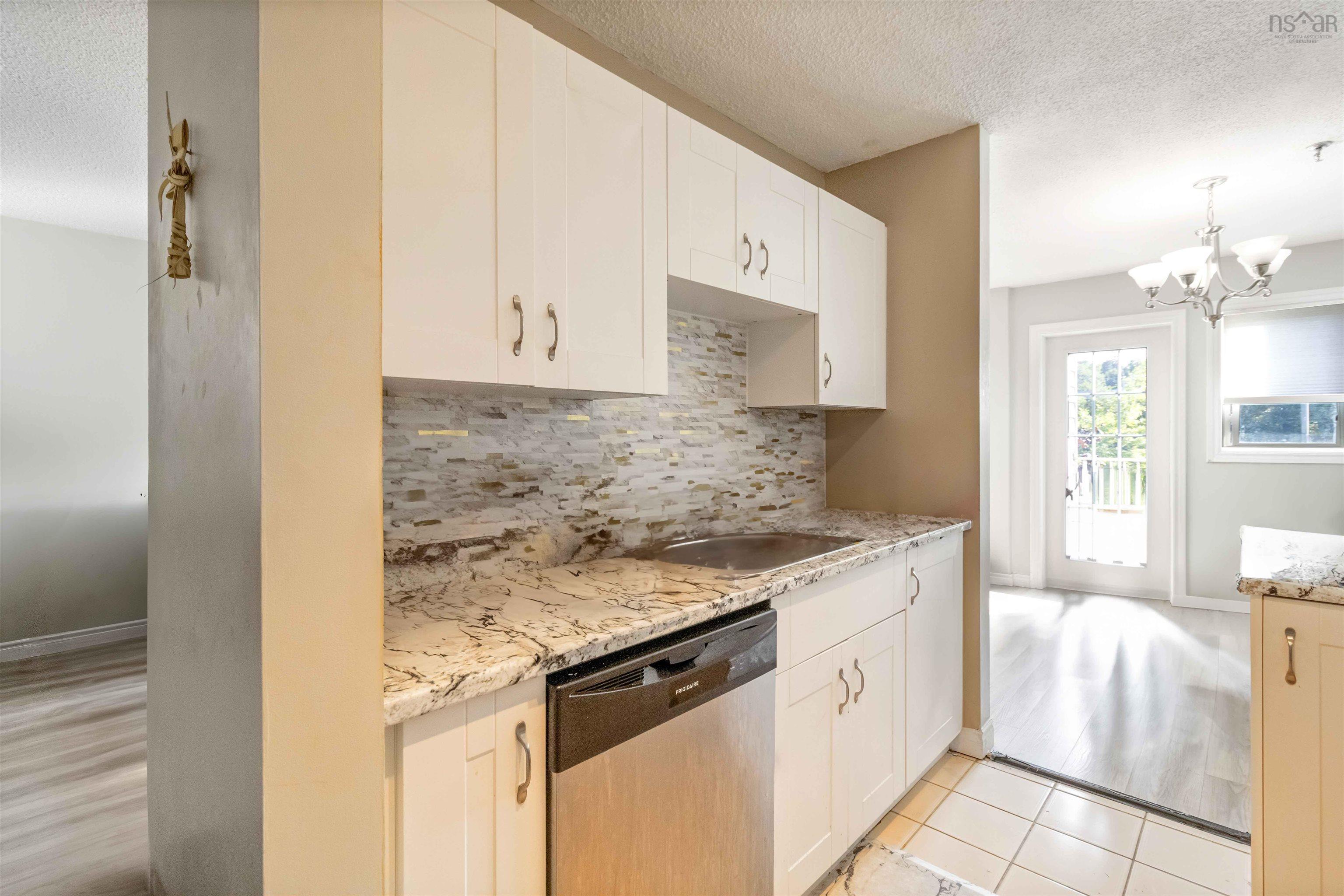 Kitchen with a textured ceiling, stainless steel dishwasher, backsplash, white cabinetry, and a chandelier