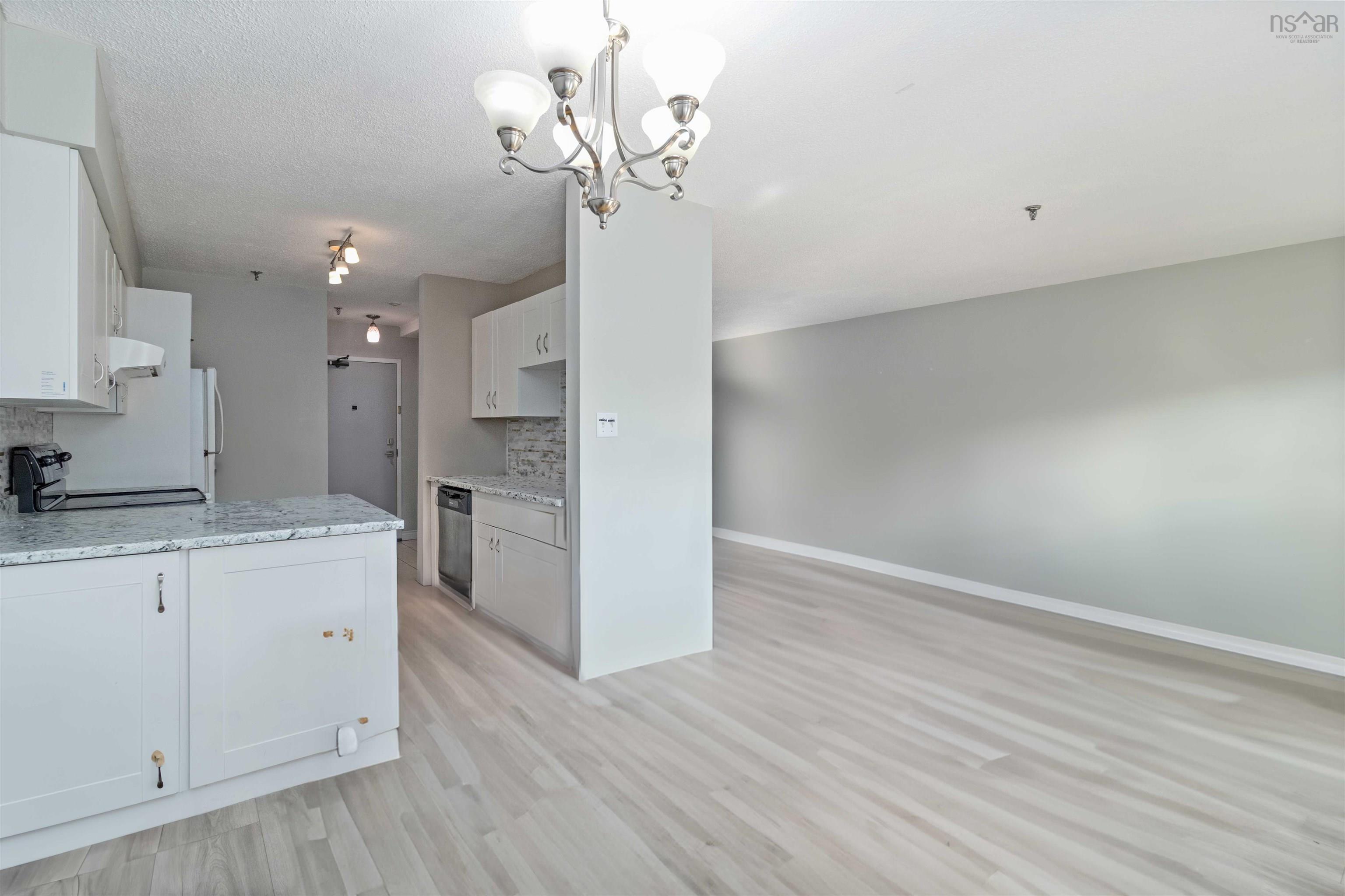 Kitchen with backsplash, light wood-type flooring, white cabinetry, stove, and a chandelier