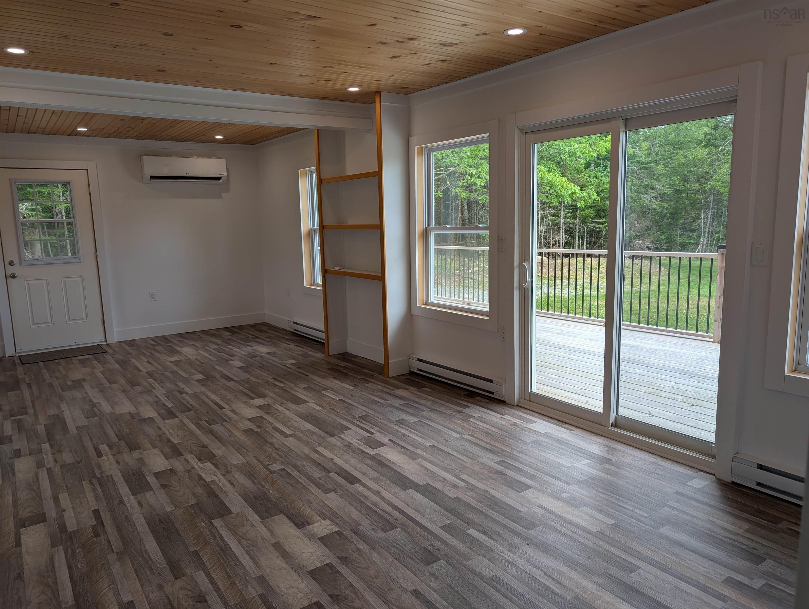 Unfurnished room featuring wood ceiling, wood finished floors, baseboard heating, a wall mounted air conditioner, and recessed lighting