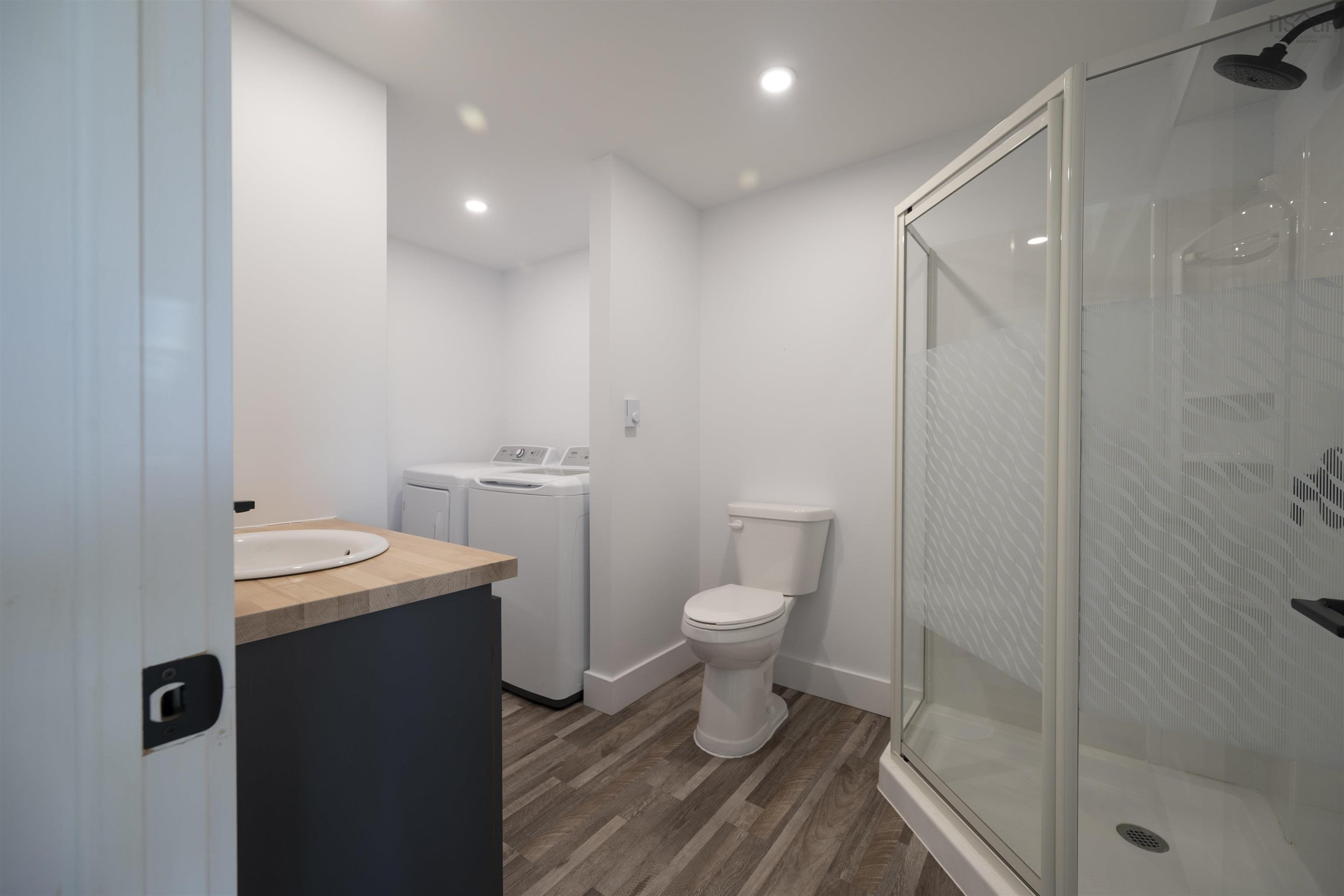 Full bathroom with washing machine and dryer, vanity, wood finished floors, a stall shower, and recessed lighting