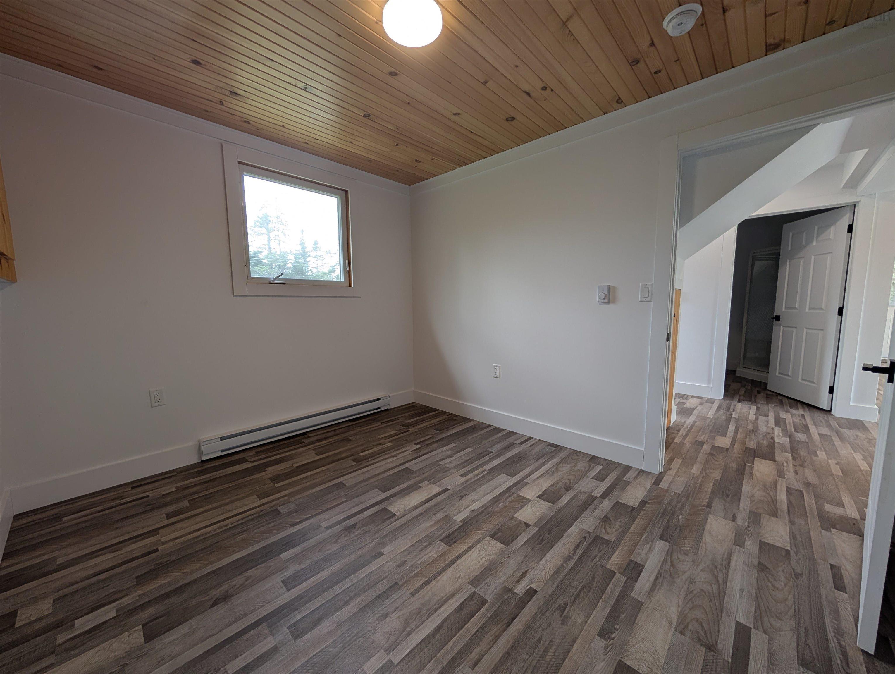 Spare room featuring baseboard heating, wooden ceiling, wood finished floors, and a smoke detector