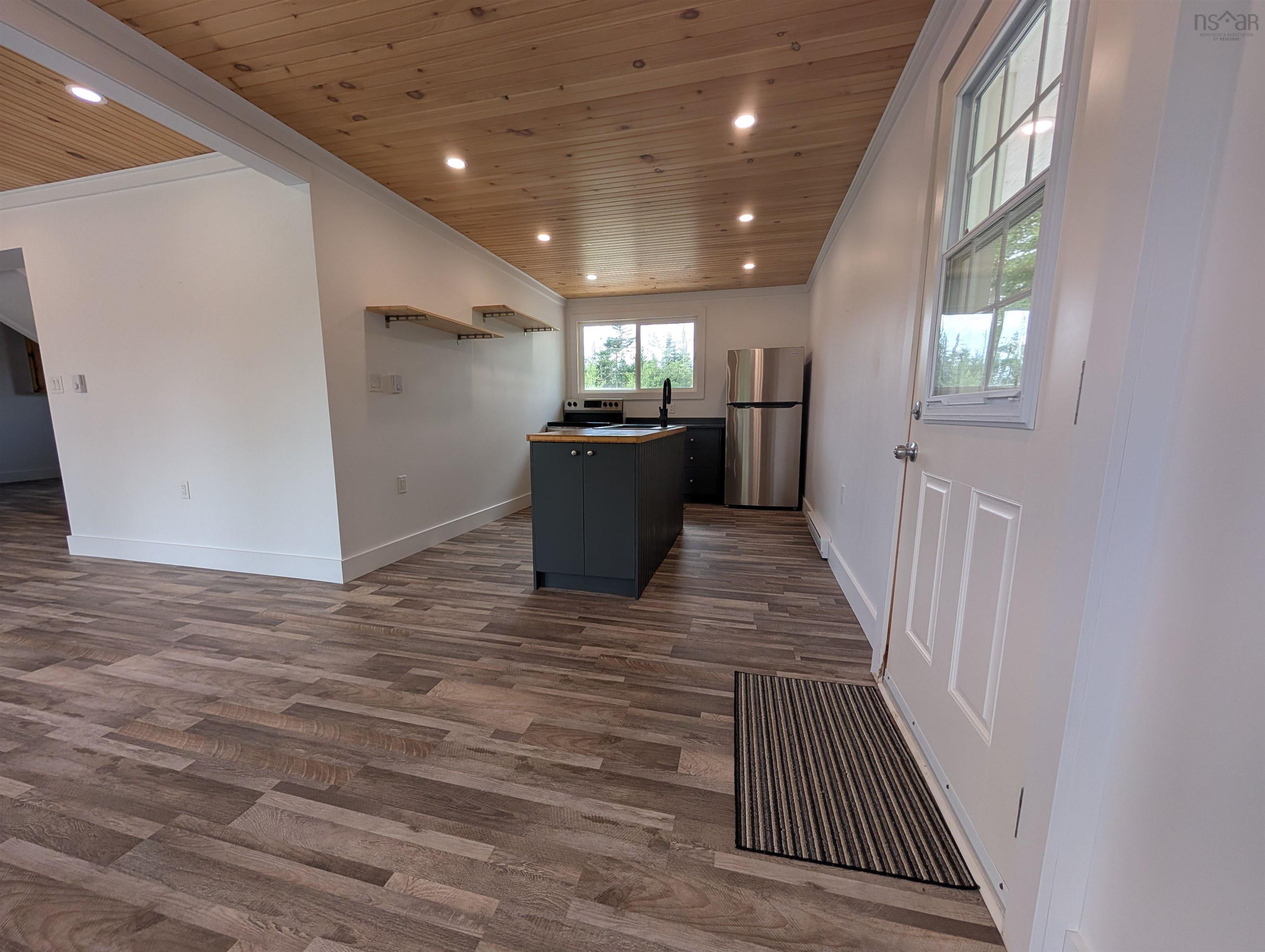 Kitchen with wooden ceiling, ornamental molding, dark wood-style flooring, freestanding refrigerator, and a center island