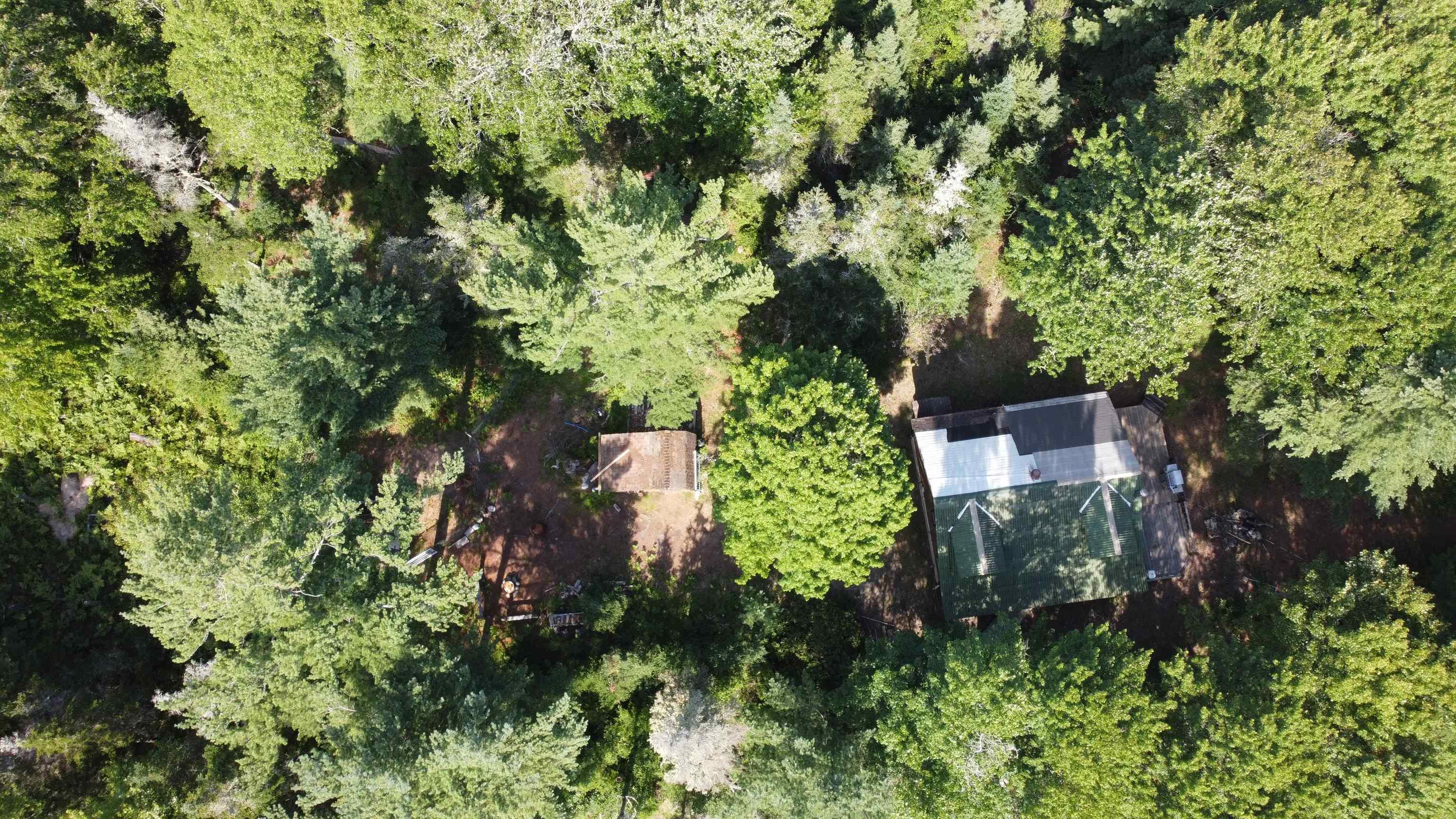 Aerial view of property and surrounding area featuring a forest