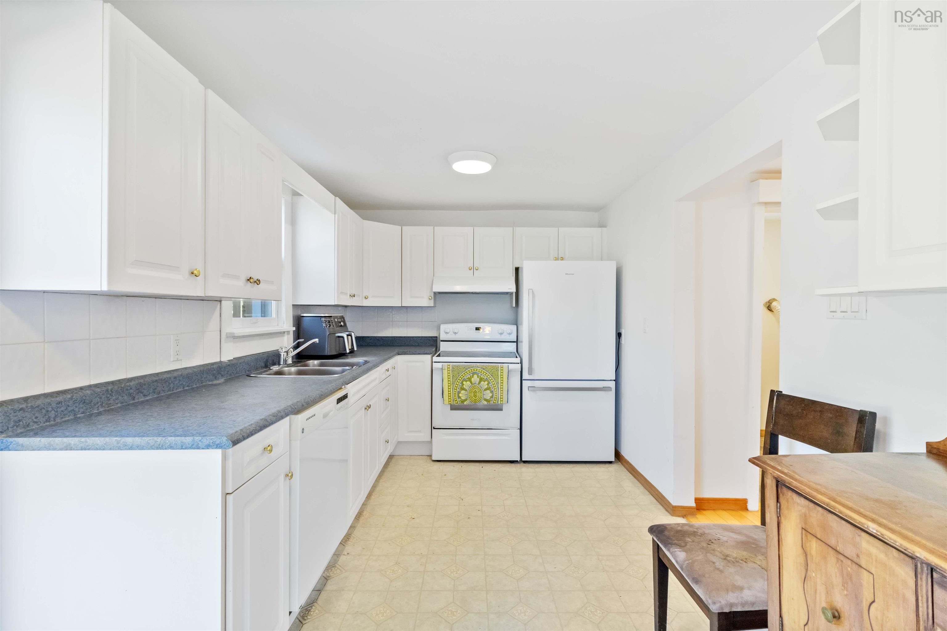 Kitchen with light flooring, white appliances, white cabinets, dark countertops, and tasteful backsplash