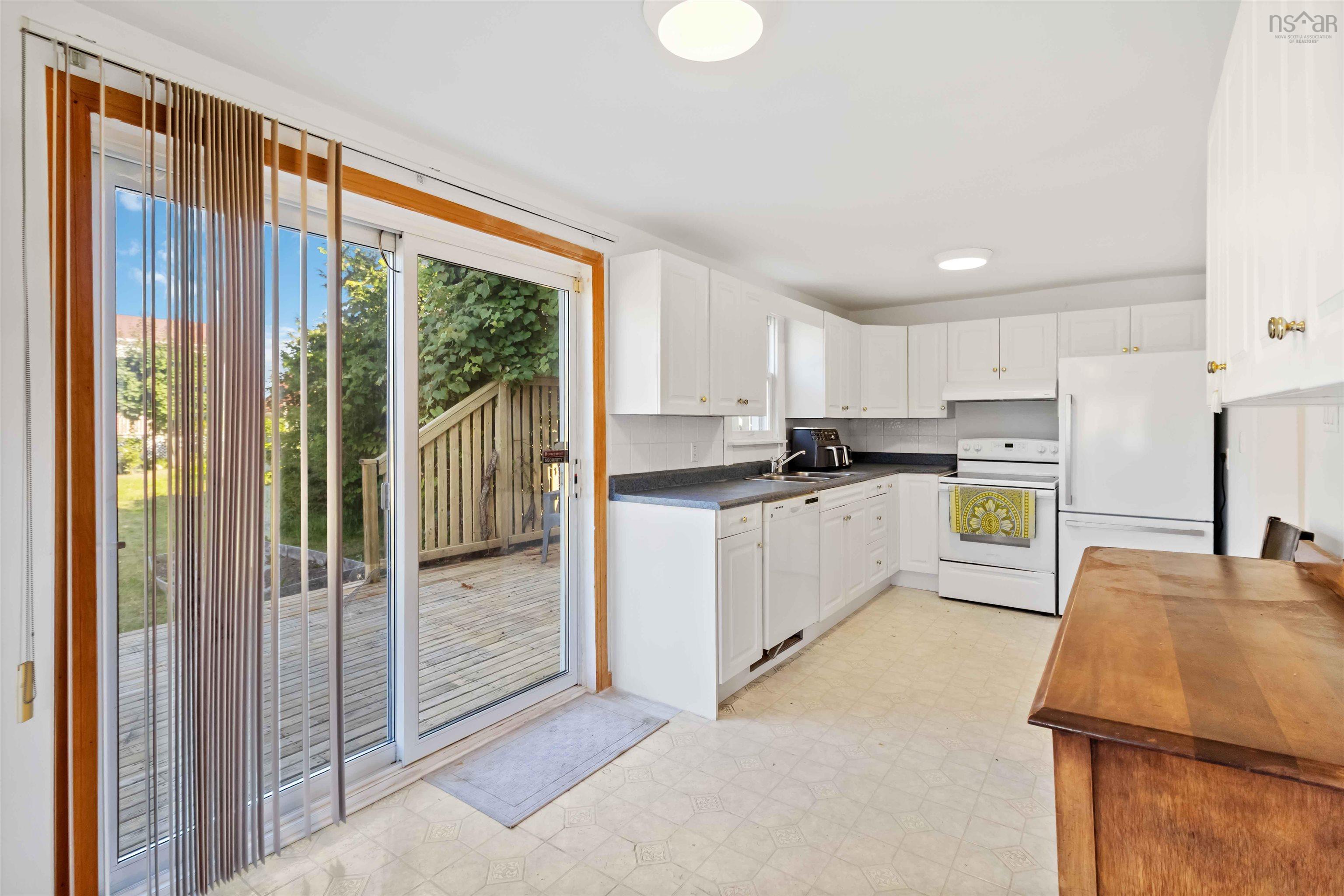 Kitchen with light floors, white cabinets, white appliances, decorative backsplash, and countertops