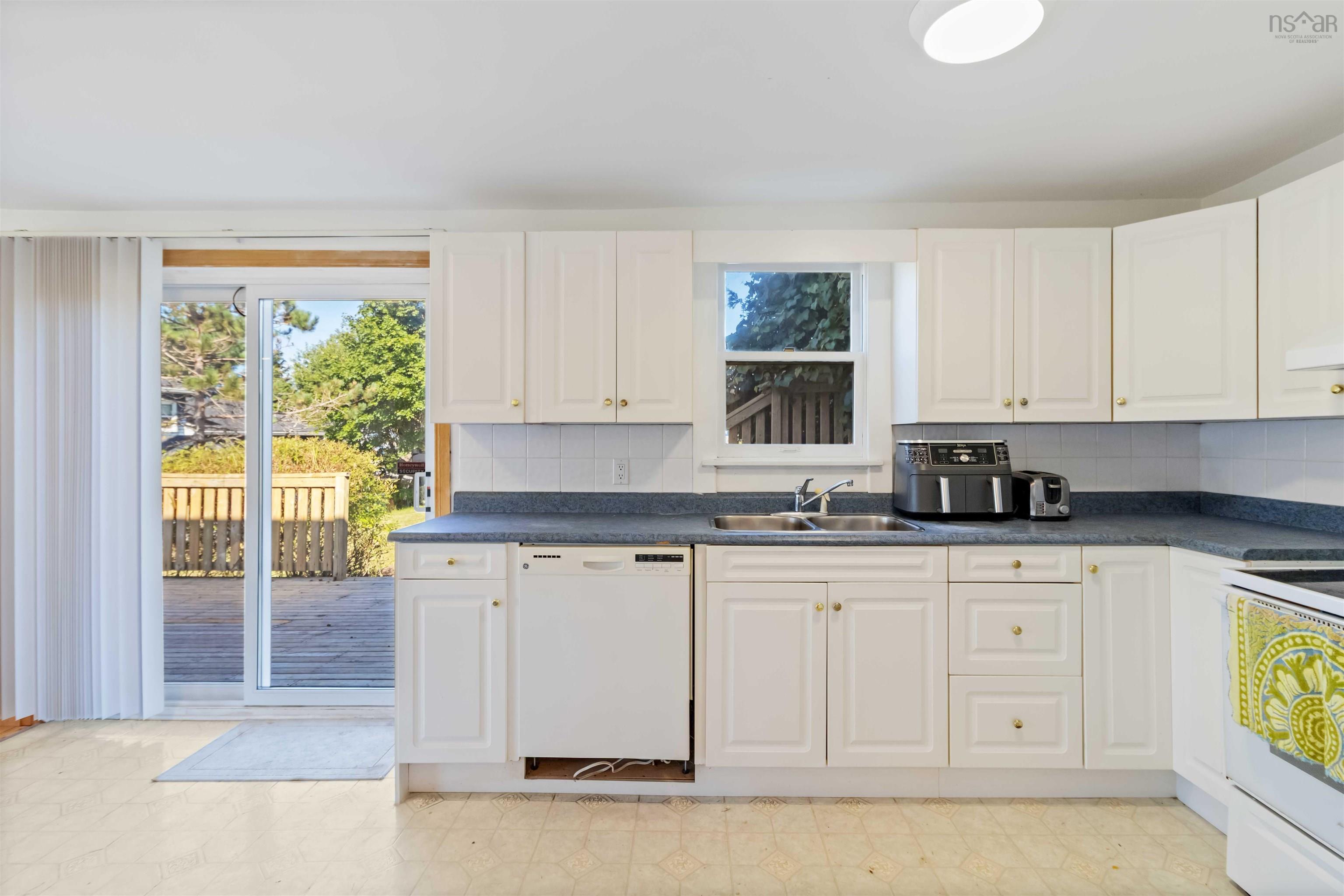 Kitchen with light floors, dark countertops, white appliances