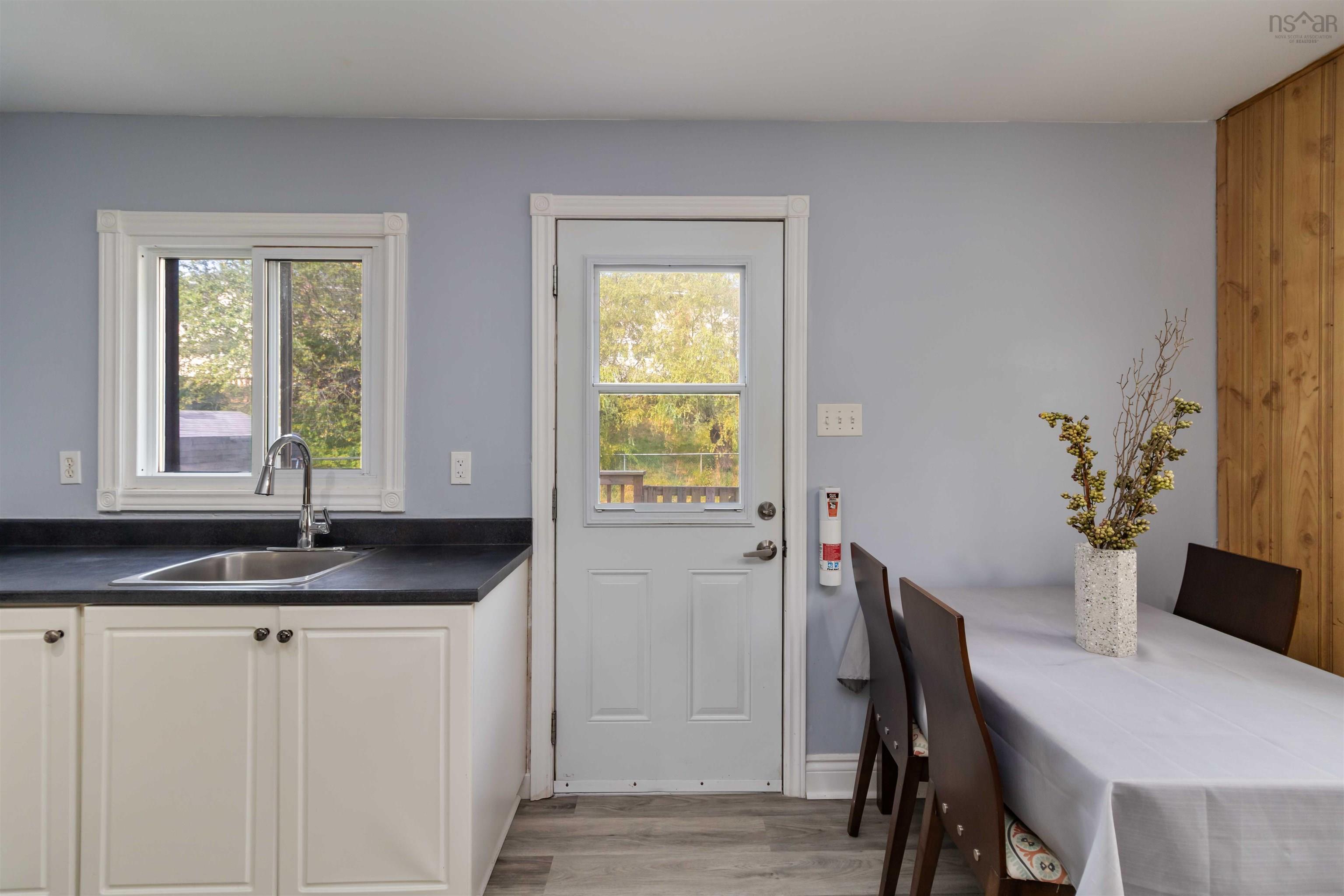 Kitchen with plenty of natural light, white cabinets, and dark countertops