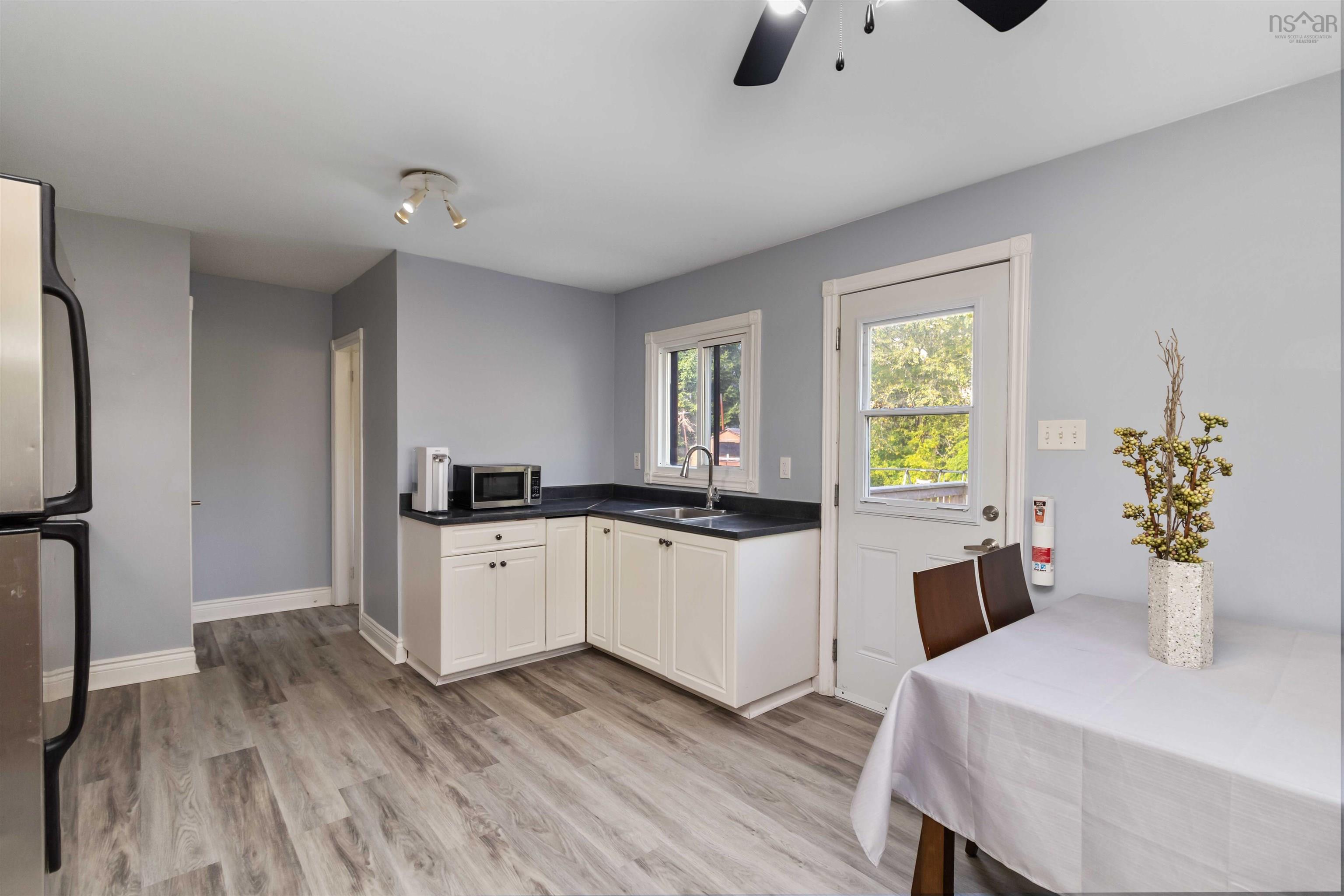 Kitchen with stainless steel appliances, dark countertops, white cabinets