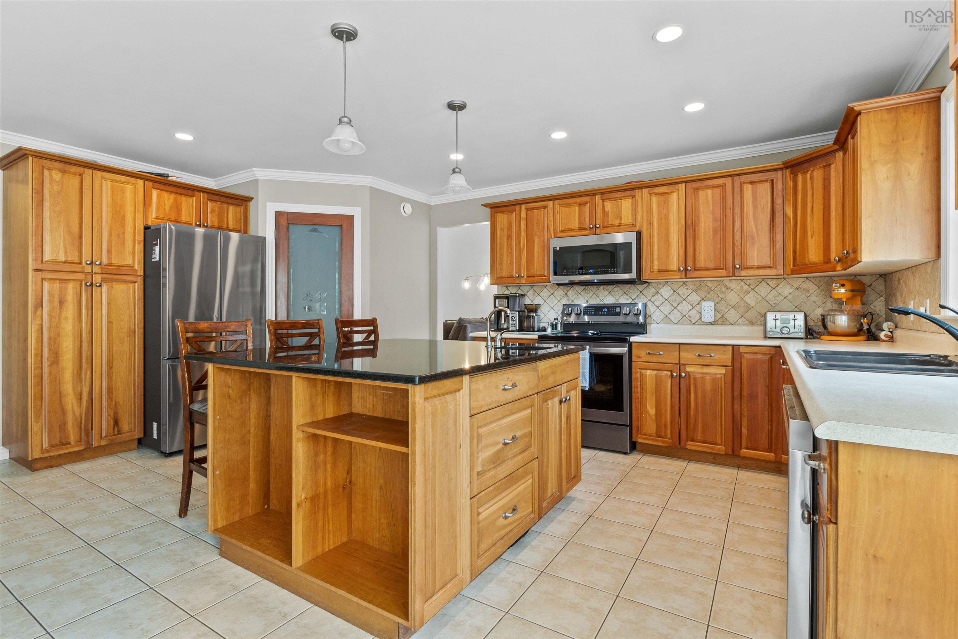 Kitchen with light tile patterned flooring, stainless steel appliances, open shelves, ornamental molding, and hanging light fixtures