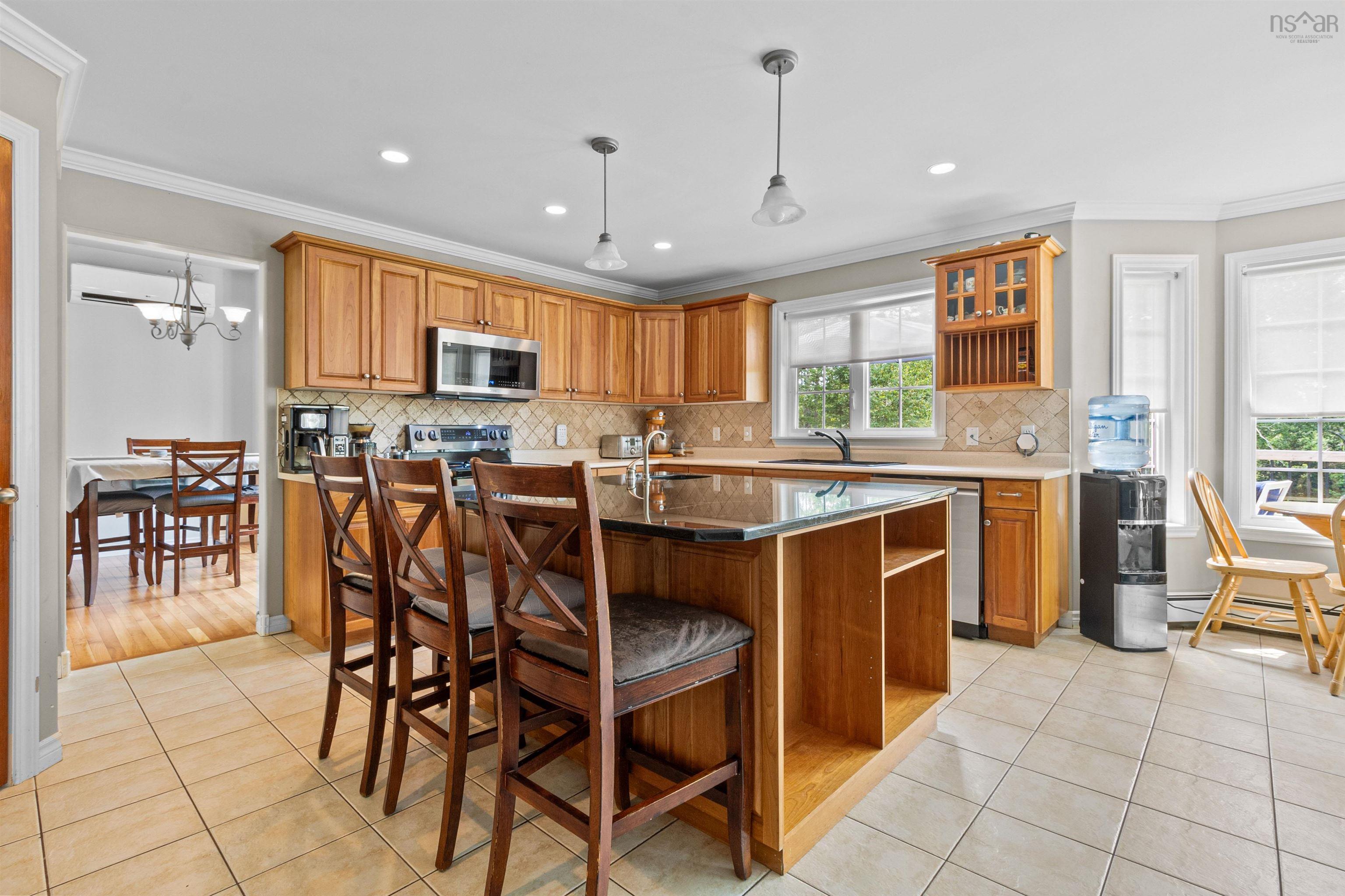 Kitchen featuring brown cabinetry, tasteful backsplash, a breakfast bar area, a kitchen island with sink, and ornamental molding