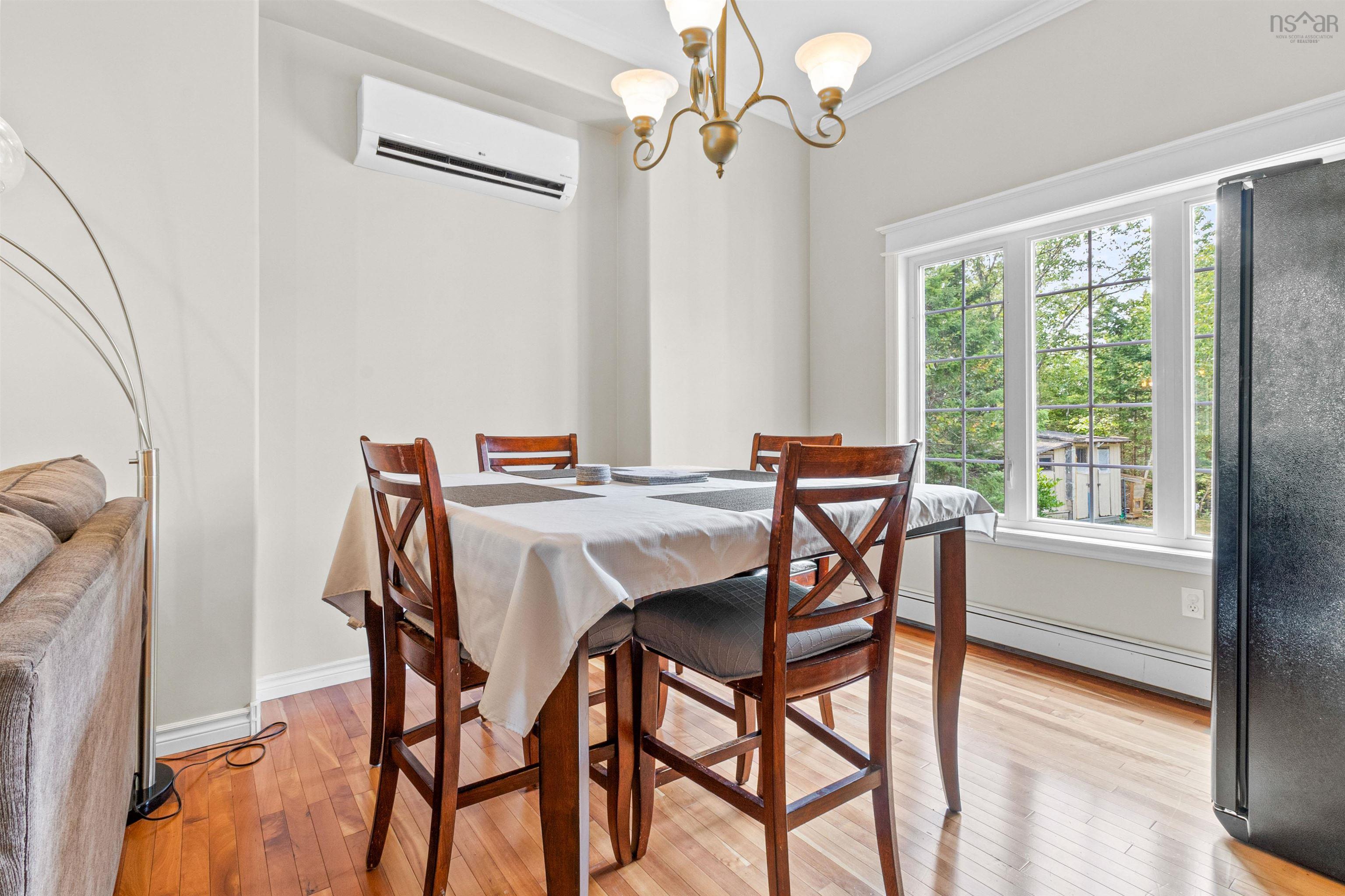 Dining space featuring light wood-style flooring, a chandelier, an AC wall unit, and ornamental molding
