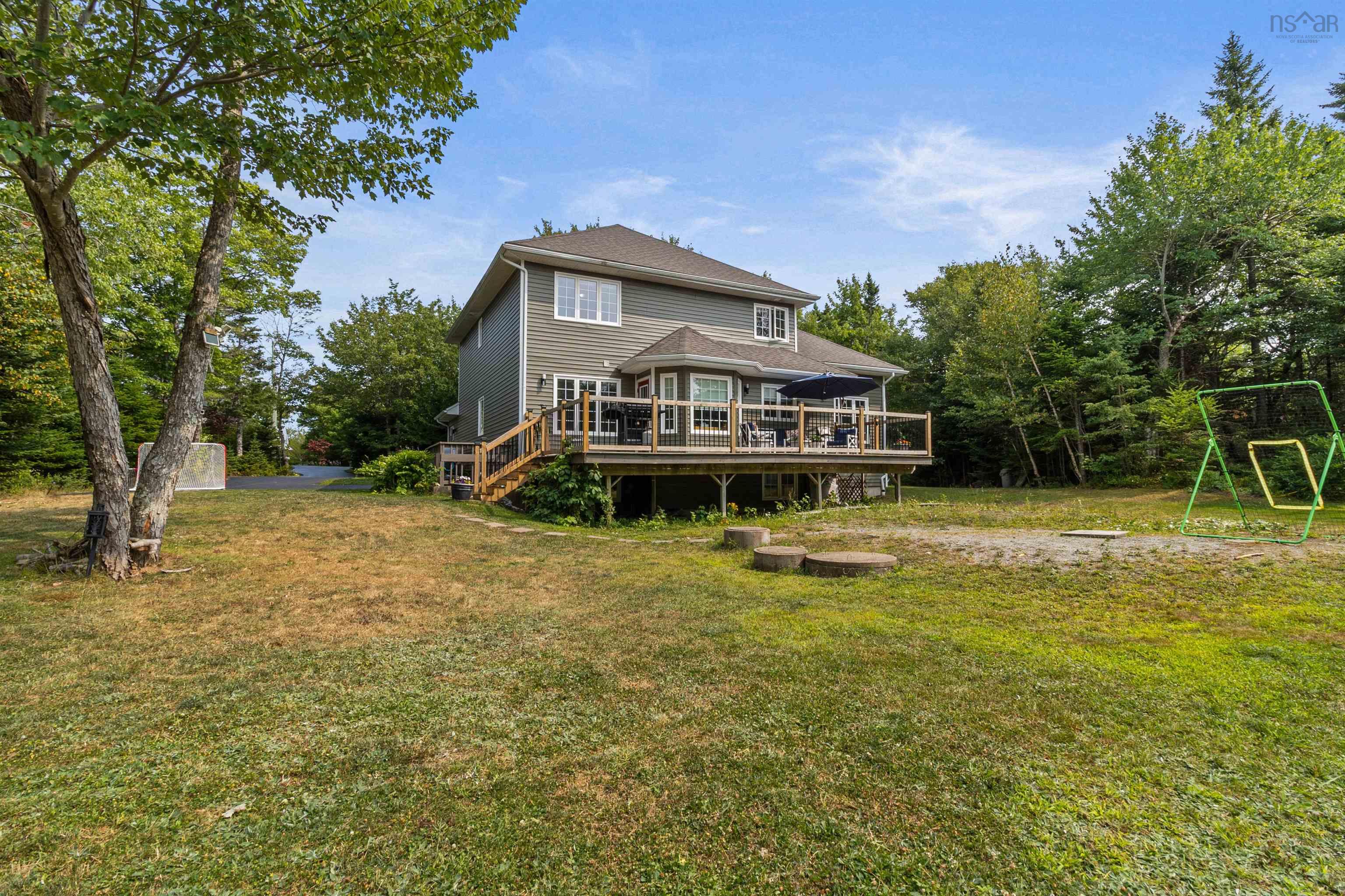 Back of property with a wooden deck, a yard, and stairway