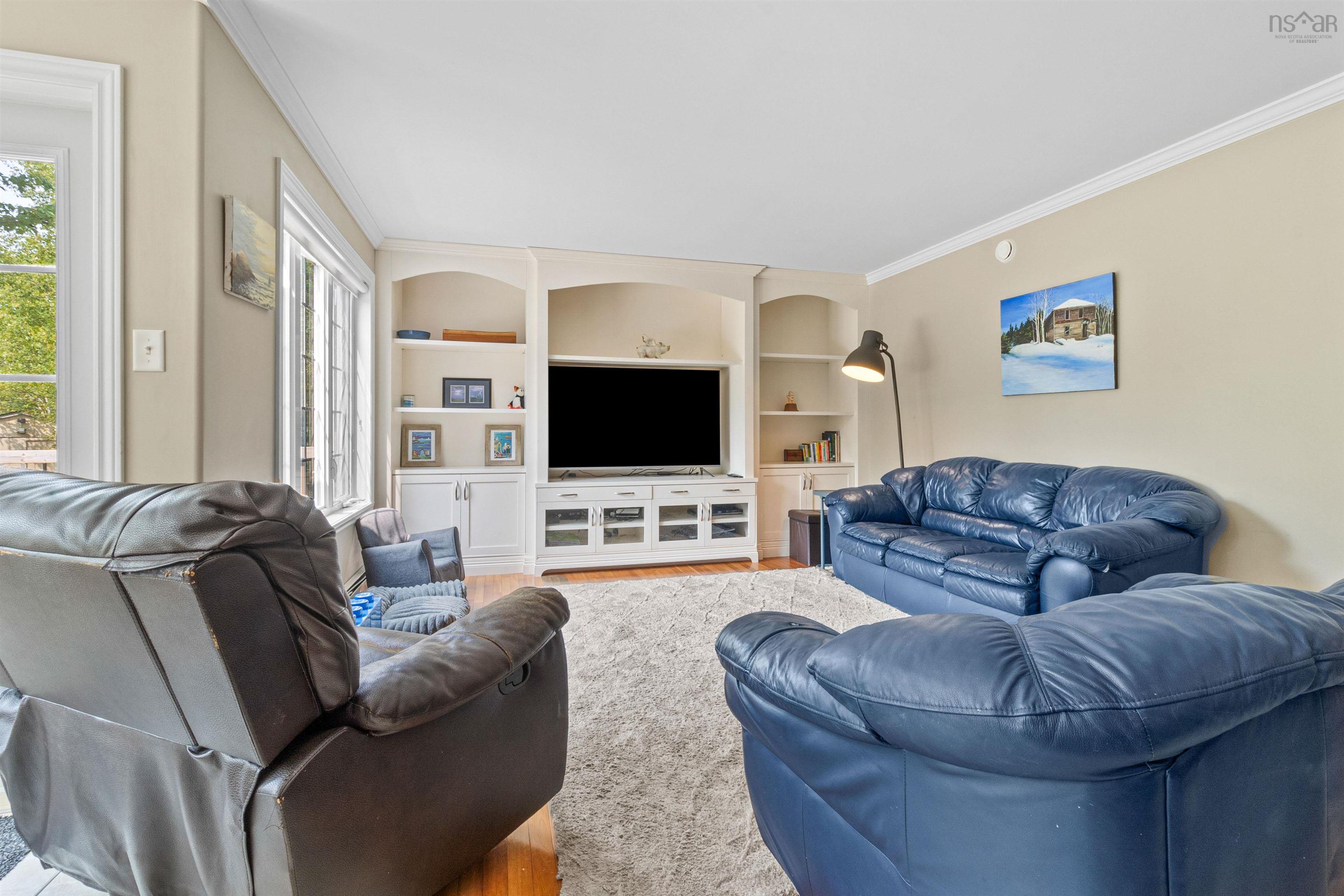 Living room featuring crown molding, built in shelves, and wood finished floors