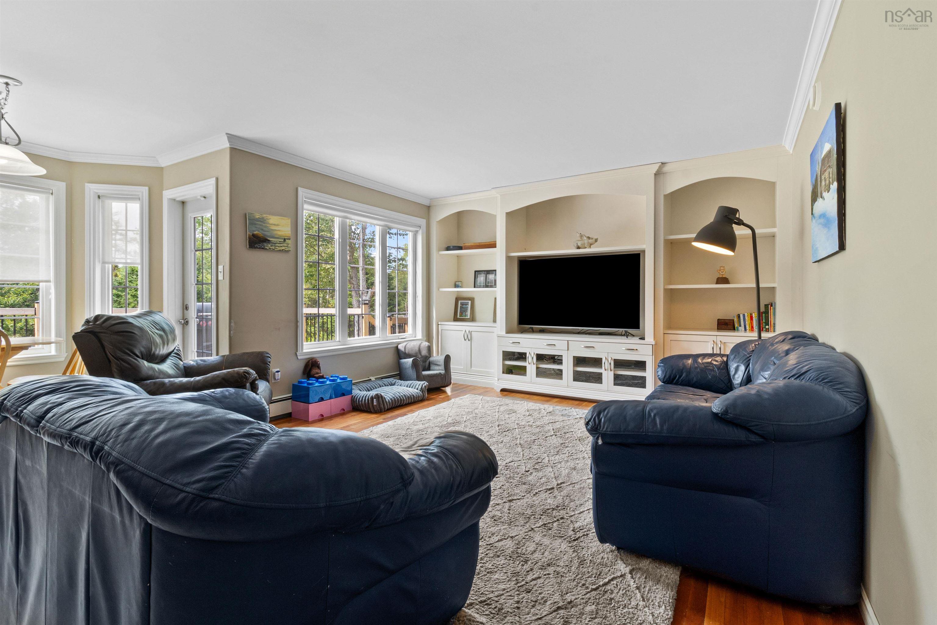 Living room featuring wood finished floors, built in shelves, and ornamental molding