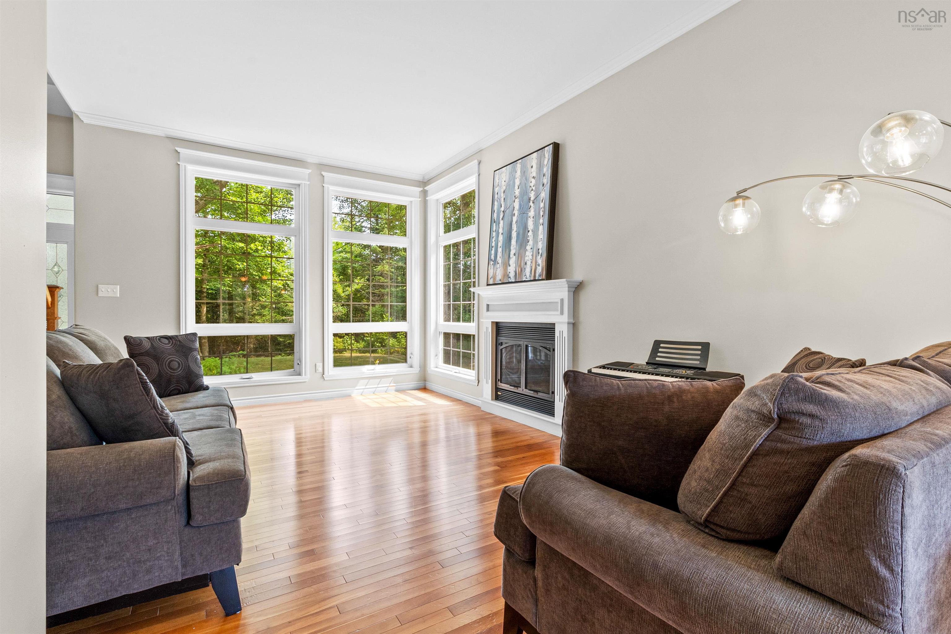 Living room featuring a glass covered fireplace, ornamental molding, and light wood finished floors