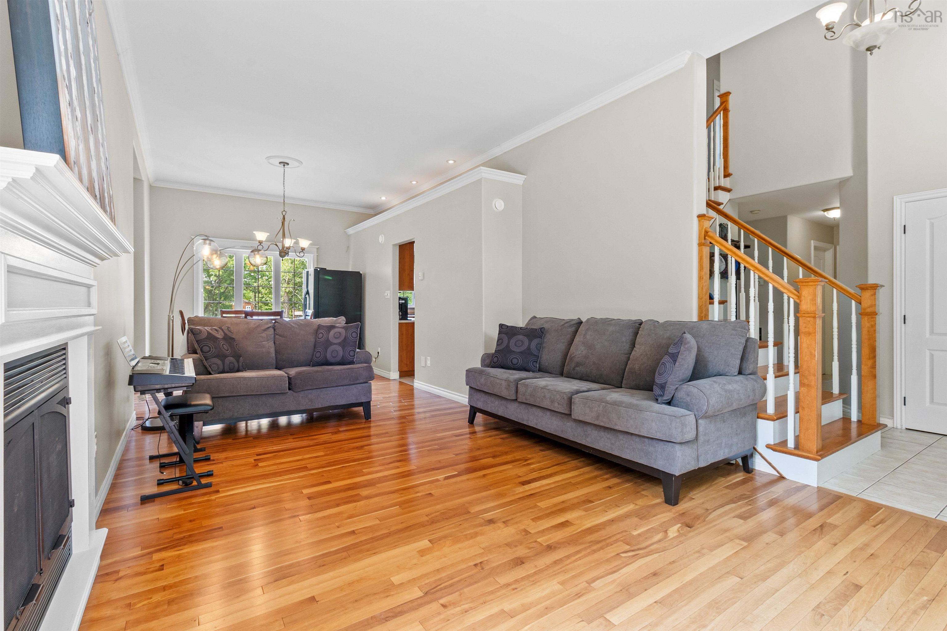 Living room with a chandelier, crown molding, a fireplace, light wood-style floors, and stairway