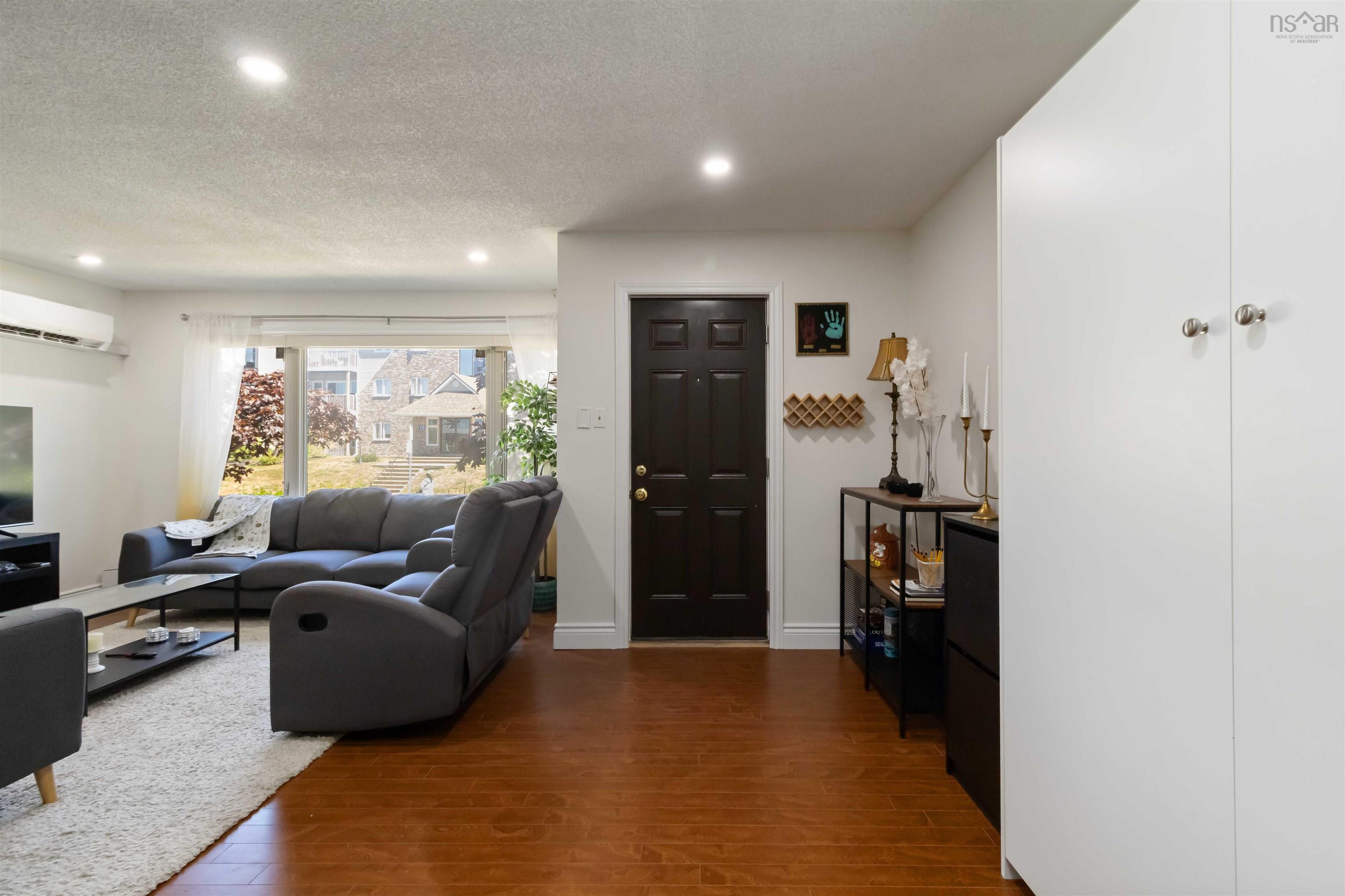 Living room with wood finished floors, a textured ceiling, recessed lighting, and a wall mounted air conditioner