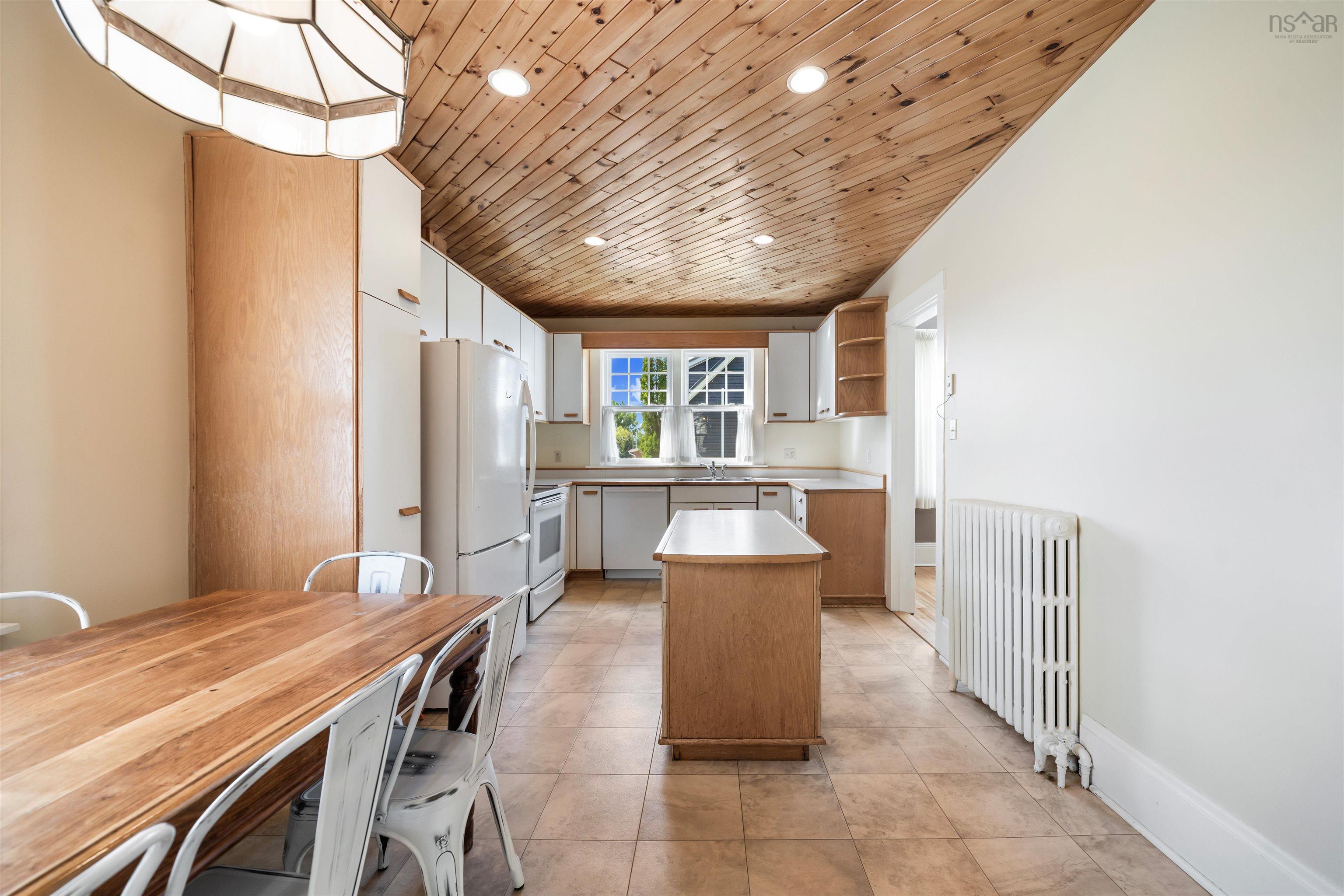 Kitchen featuring open shelves, wooden ceiling, radiator, light countertops, and white appliances