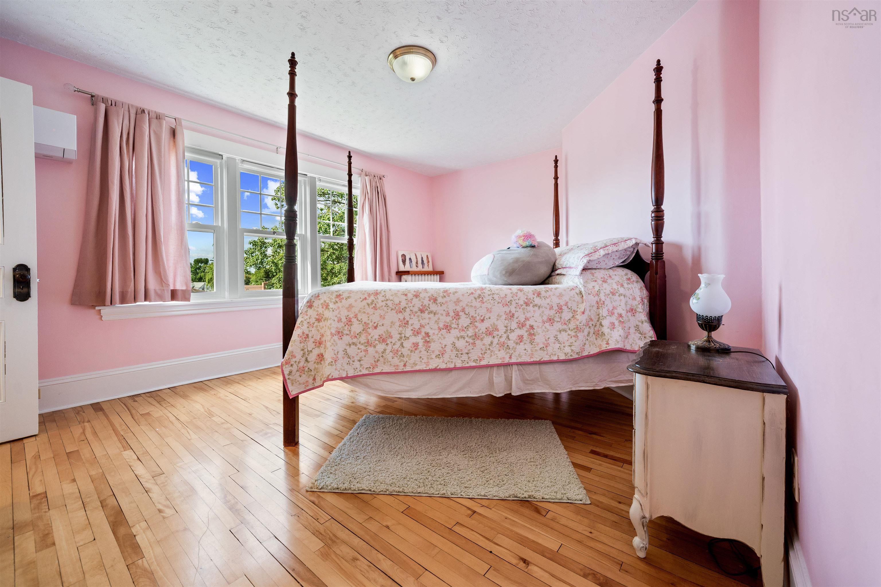 Bedroom with a textured ceiling, light wood-style flooring, and a wall mounted air conditioner